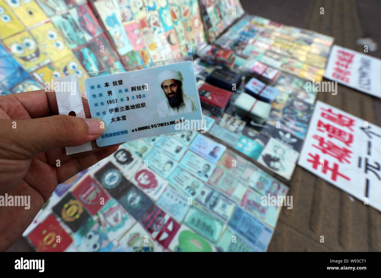 Un uomo mostra un fake cinese scheda ID dell ex leader di Al Qaeda Osama bin Laden in vendita in una fase di stallo su di una strada nella città di Guangzhou, sud Chinas Guangdong Foto Stock