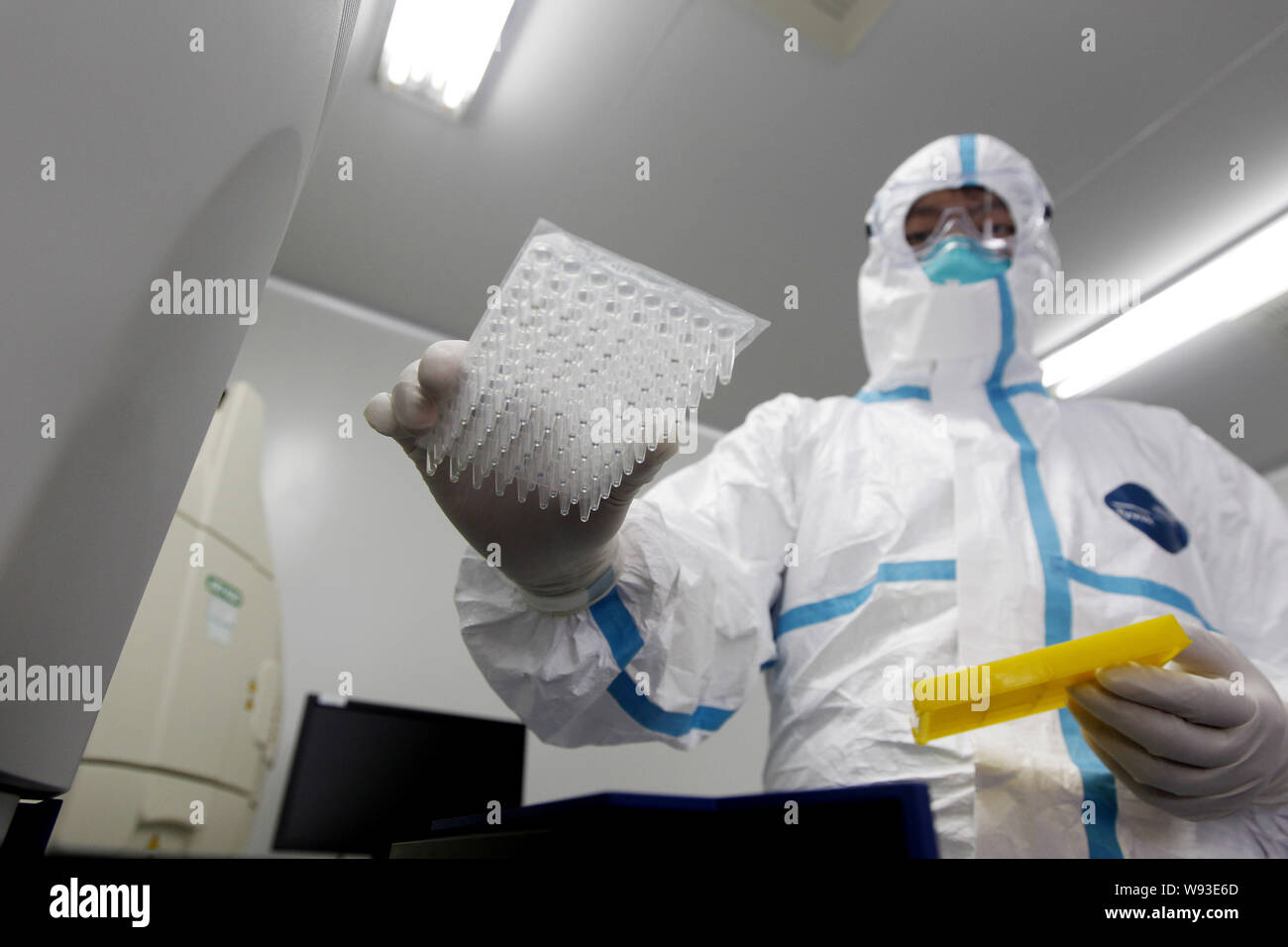 Un ricercatore cinese, vestita di indumenti di protezione, prove di virus influenzali nel laboratorio di Kunming Centro municipale per il controllo delle malattie e indietroe Foto Stock