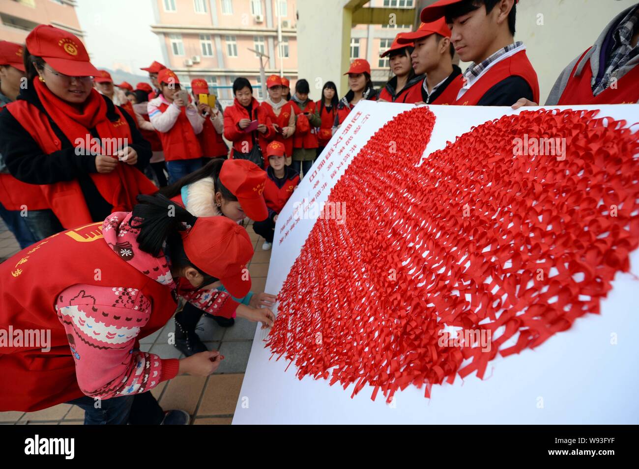 Volontari provenienti da una scuola medica di pasta nastri rossi a formare un cuore gigante su una scheda a un HIV/AIDS campagna di sensibilizzazione nella città di Nanchong, southwest mento Foto Stock