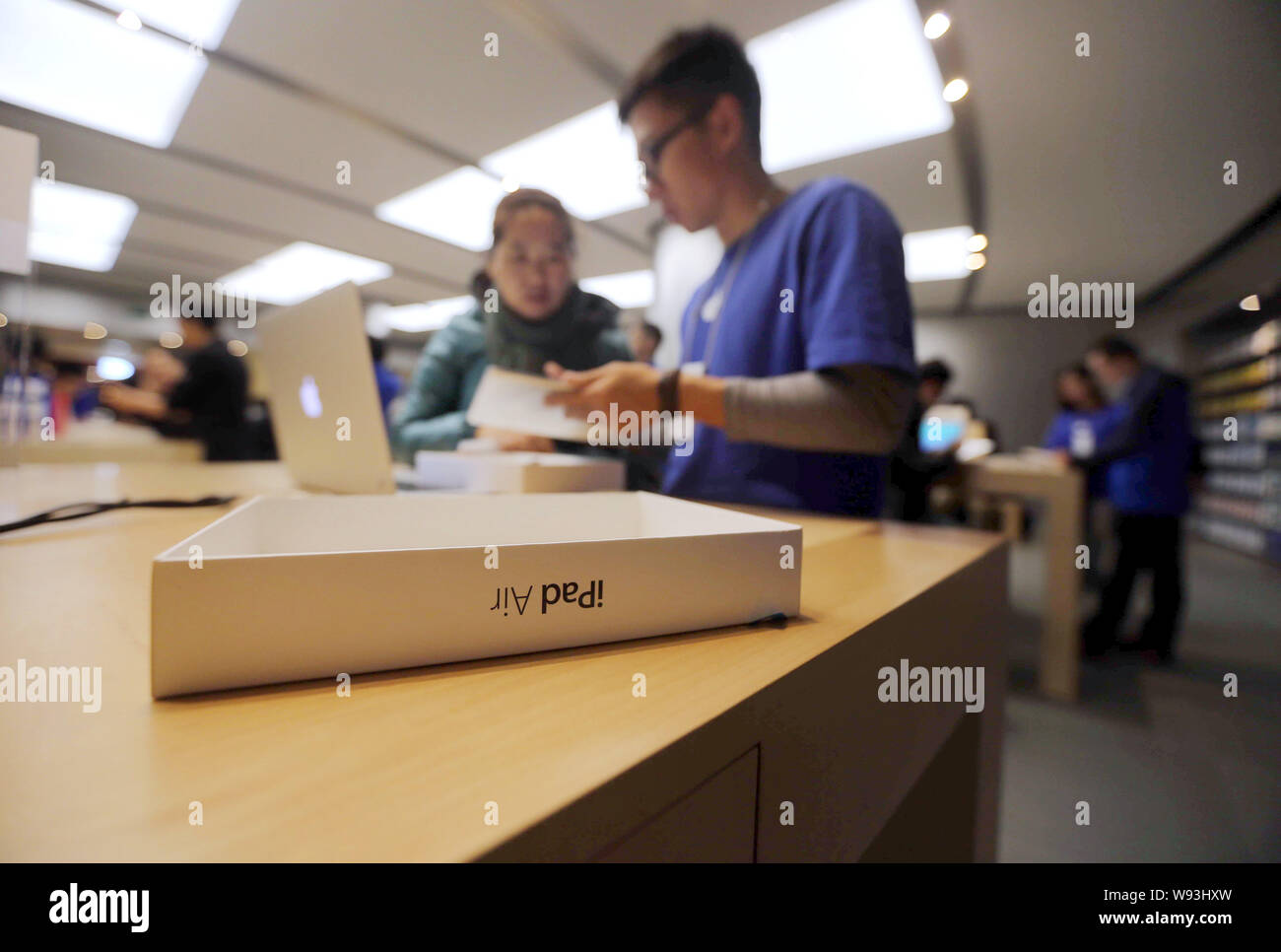 I dipendenti cinesi assistere i clienti a comprare un iPad aria tablet PC presso un negozio Apple Store in Cina, 1 novembre 2013. Apple Inc. ha lanciato il suo nuovo iPad Foto Stock