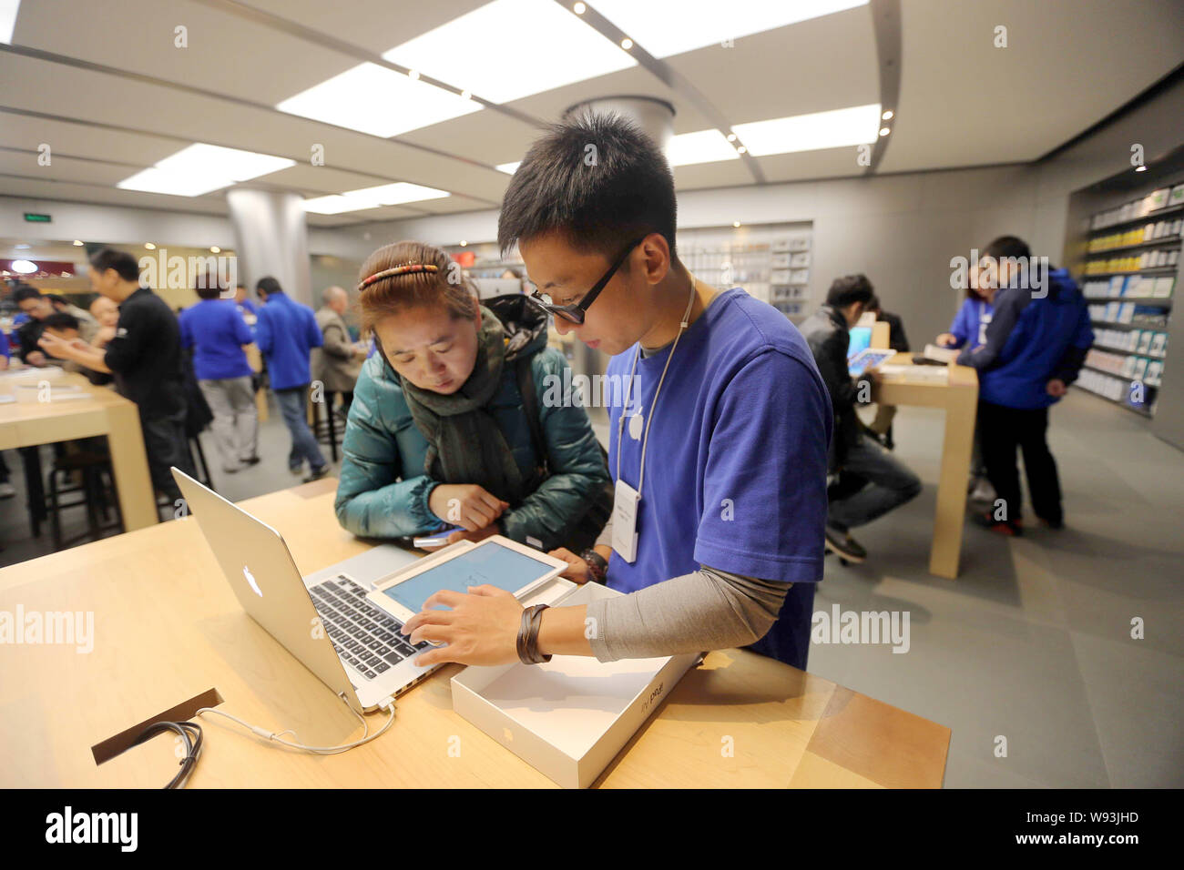 I dipendenti cinesi assistere i clienti a comprare un iPad aria tablet PC presso un negozio Apple Store in Cina, 1 novembre 2013. Apple Inc. ha lanciato il suo nuovo iPad Foto Stock