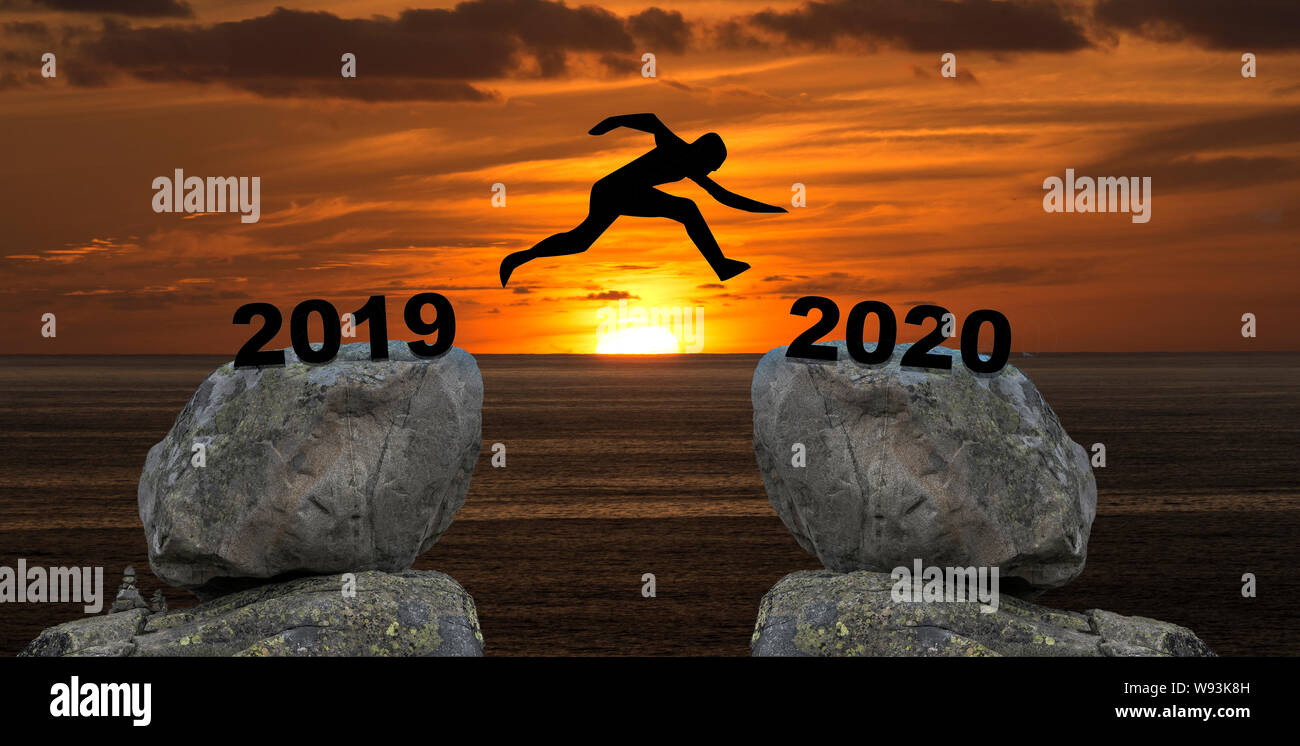Un uomo salto tra 2019 e 2020 anni da una roccia per un altro rock durante il tramonto Foto Stock