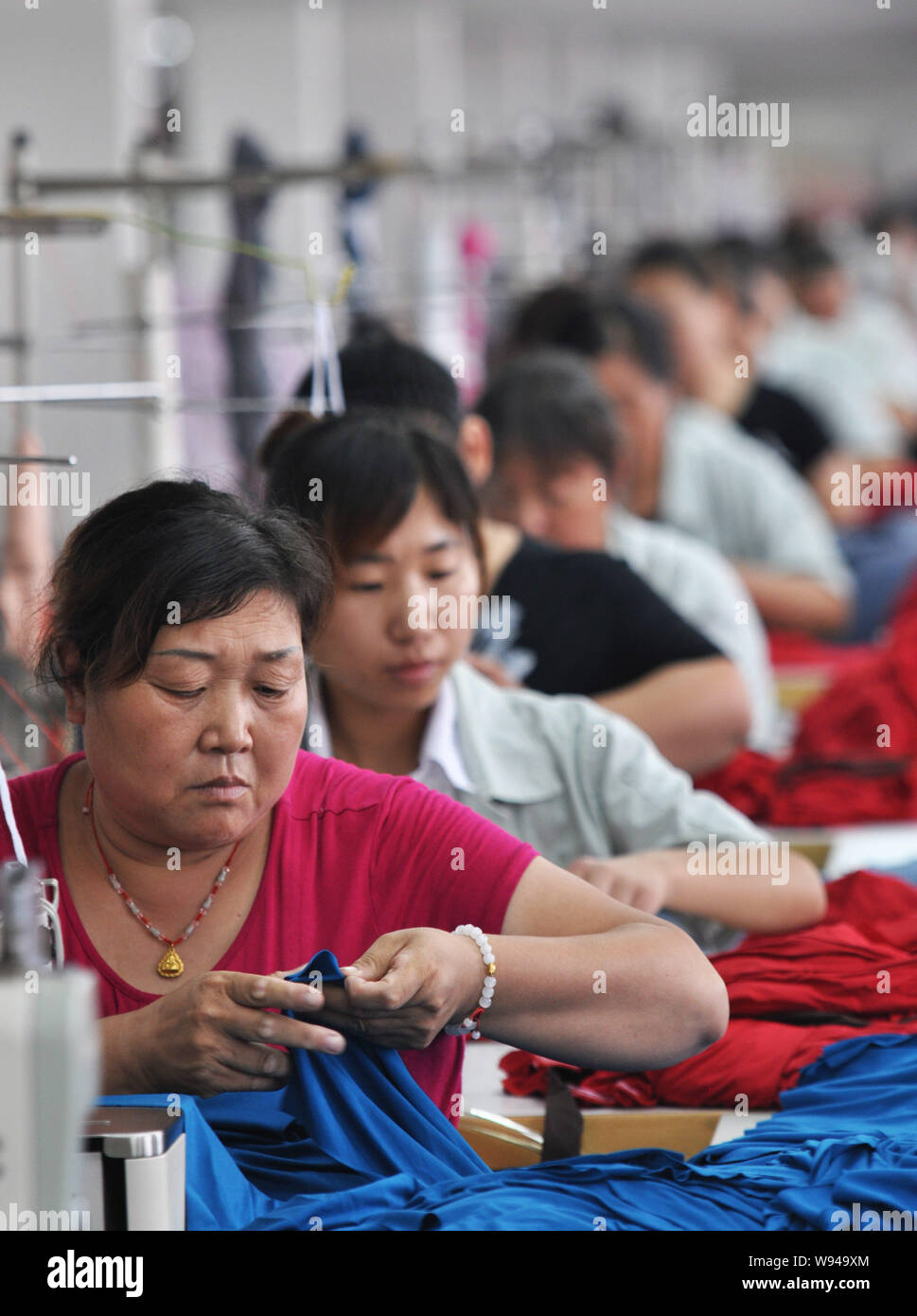--FILE--femmina di lavoratori cinesi cucire vestiti in una fabbrica in Binzhou, est Chinas provincia di Shandong, 11 settembre 2013. Porcellane activitie di fabbricazione Foto Stock