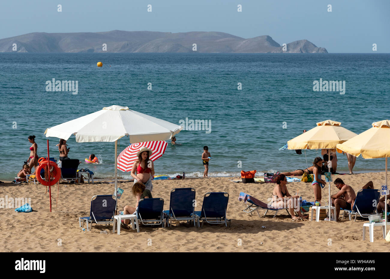 Iraklion, Creta, Grecia. Giugno 2019. Acapulco Beach si trova vicino all'aeroporto Iraklion. I turisti a prendere il sole. Dia isola disabitata in background. Foto Stock