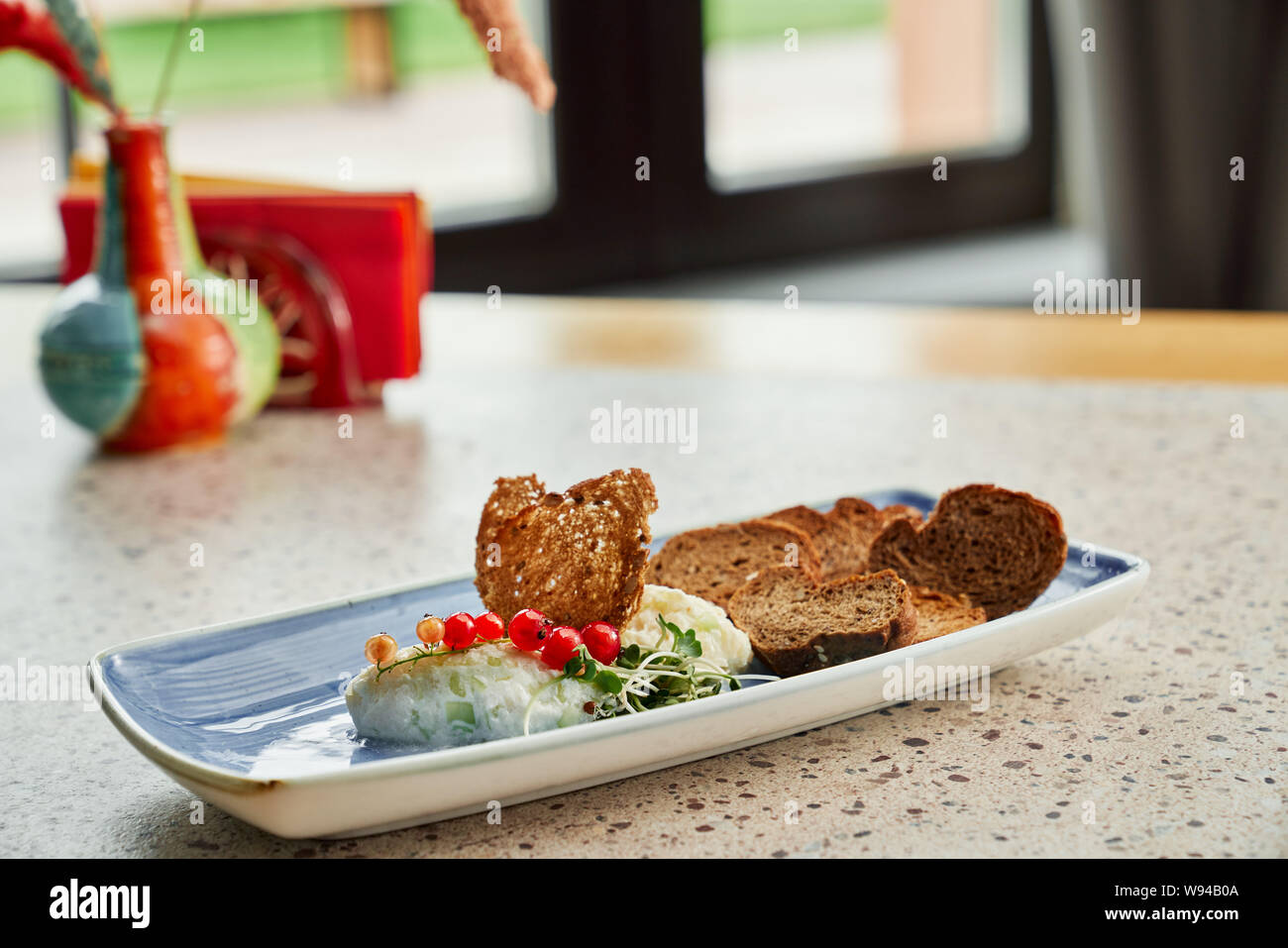 Vista dal lato di deliziosi snack giacente sulla piastra lunga in cafe. Gustosa sgranocchia servita con mirtillo palustre e squisita purea di verdure per la cena. Concetto di cucina, antipasto e cibo. Foto Stock