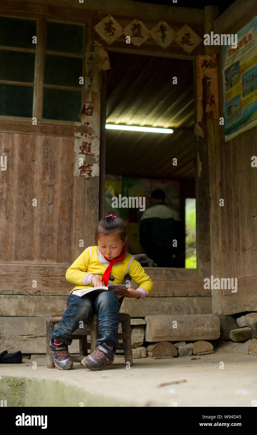 Xinxin Yu, 5 anni ragazza che ha di salita verticale di scale in legno a scuola legge un libro nella sua casa di Sangzhi County, central Chinas Hunan provin Foto Stock
