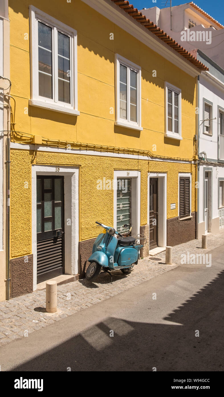 Casa Gialla con blue scooter moto parcheggiate fuori in Algarve città di Lagos in Portogallo Foto Stock