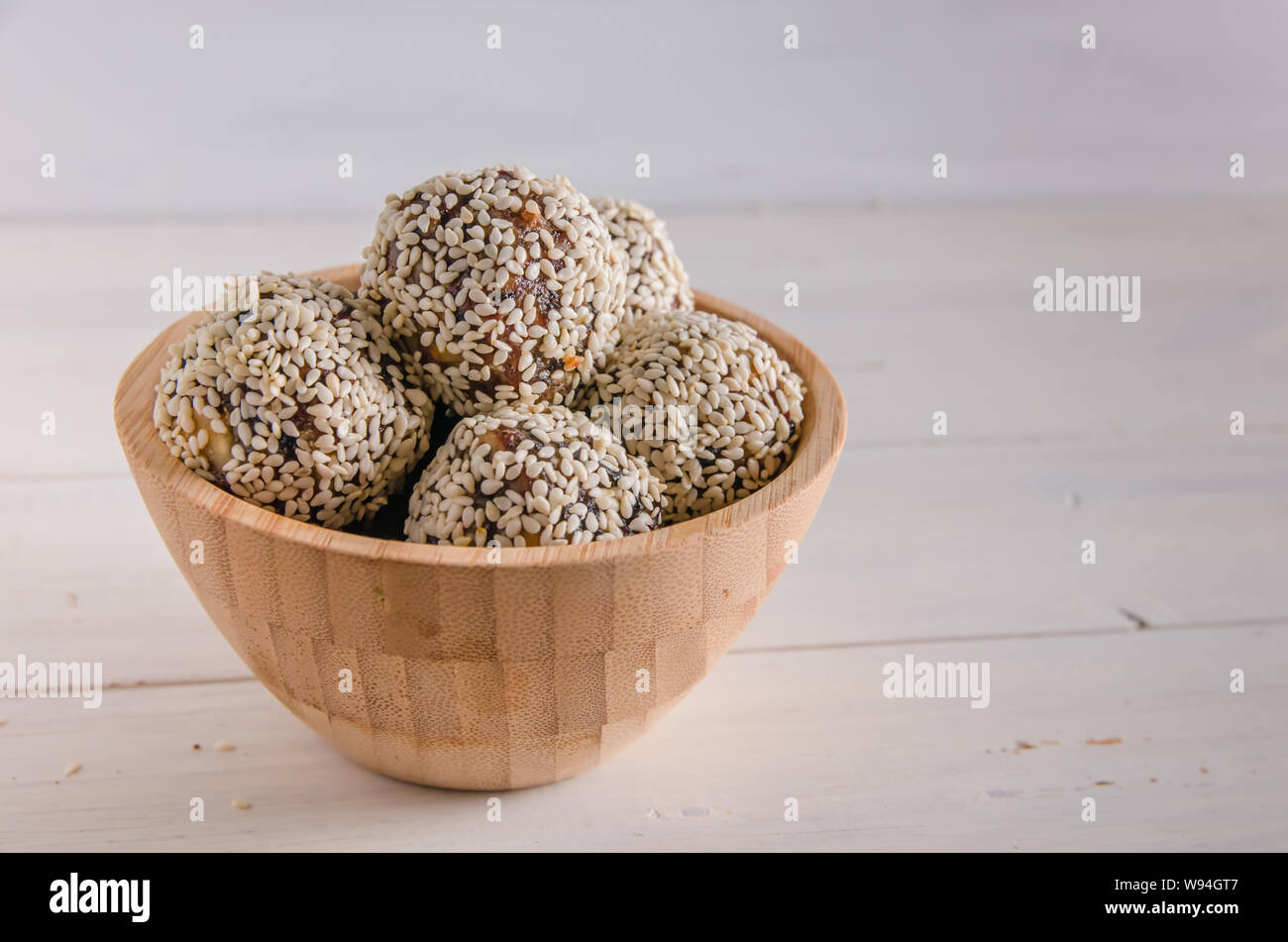 Cibo vegetariano, fatti in casa le sfere di energia di noci, datteri, prugne, mirtilli e miele con sesamo su sfondo bianco Foto Stock