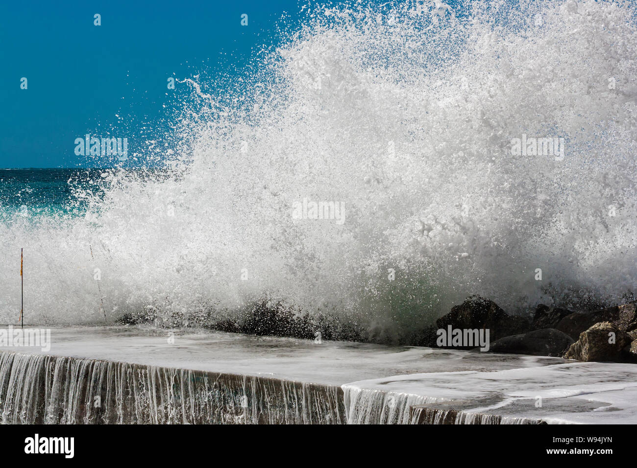 Un'onda si rompe sulla scogliera durante una tempesta di primavera nel Mar Ligure in Italia Foto Stock
