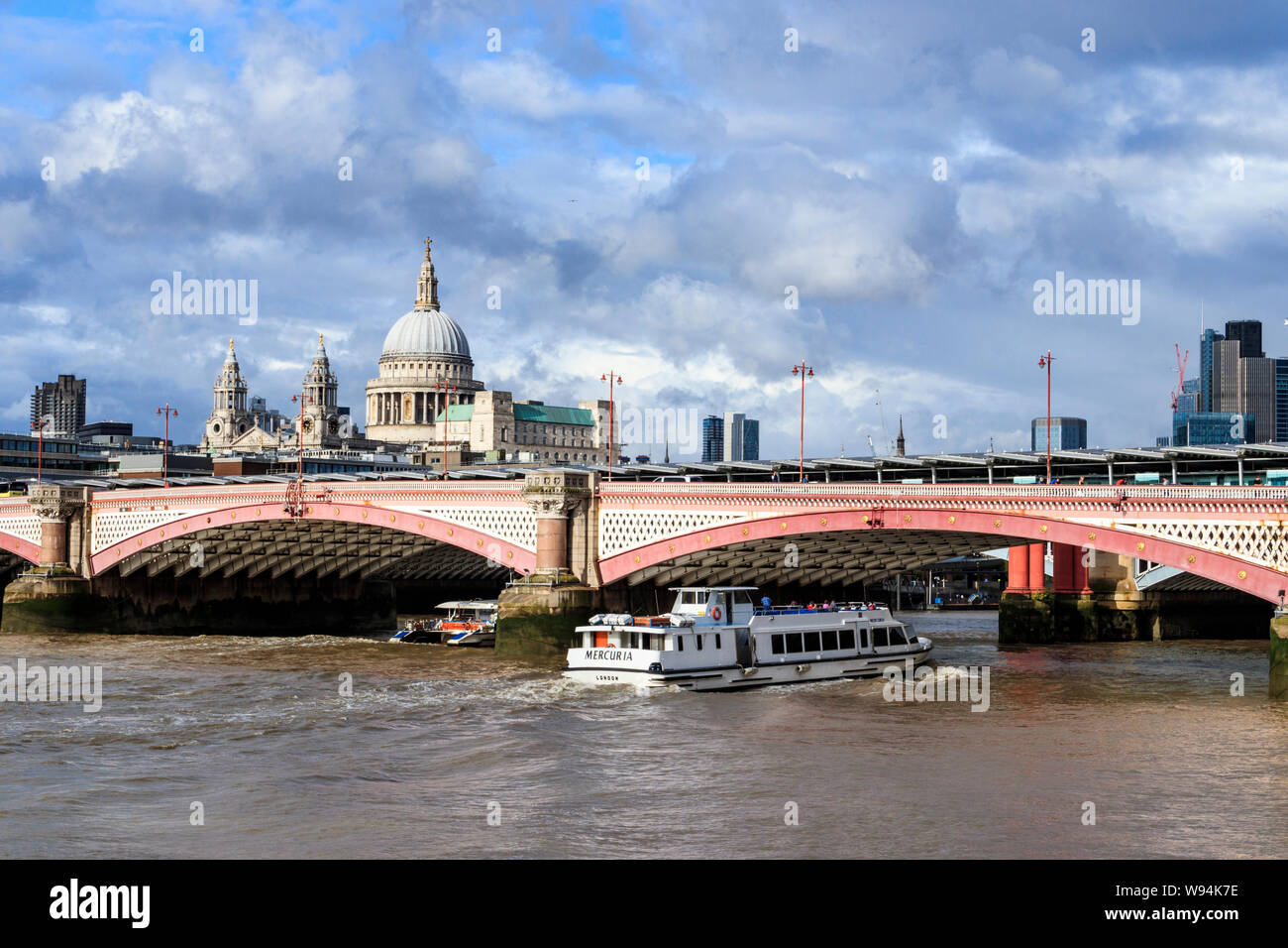 Un giro turistico in battello passa sotto il Blackfriars Bridge sul fiume Tamigi, la Cattedrale di St Paul in background, London, Regno Unito Foto Stock