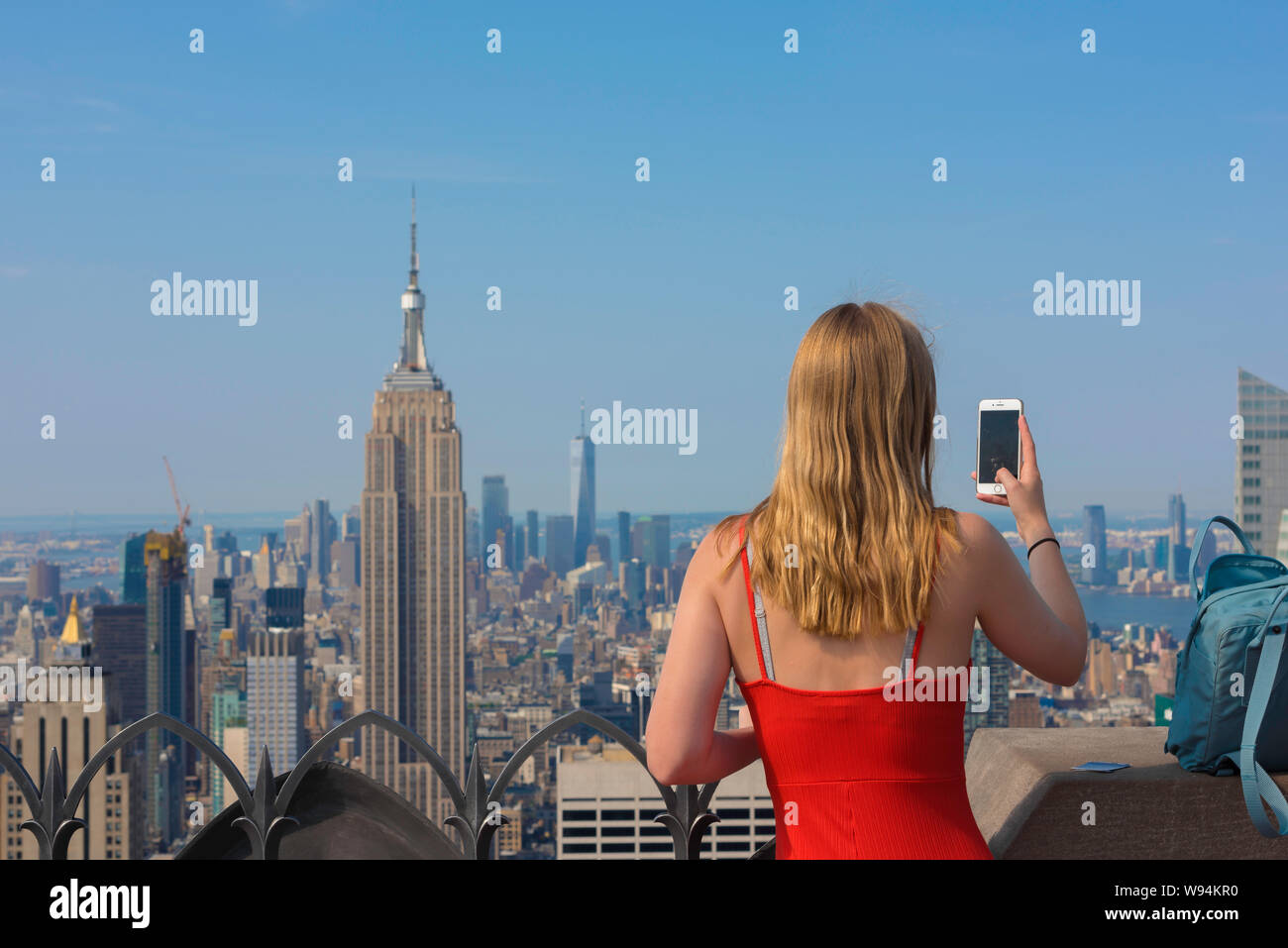 Concetto di fotografia di viaggio della donna, vista posteriore di una giovane turista femminile che scatta una foto di Manhattan con il suo telefono della macchina fotografica, New York City, Stati Uniti Foto Stock