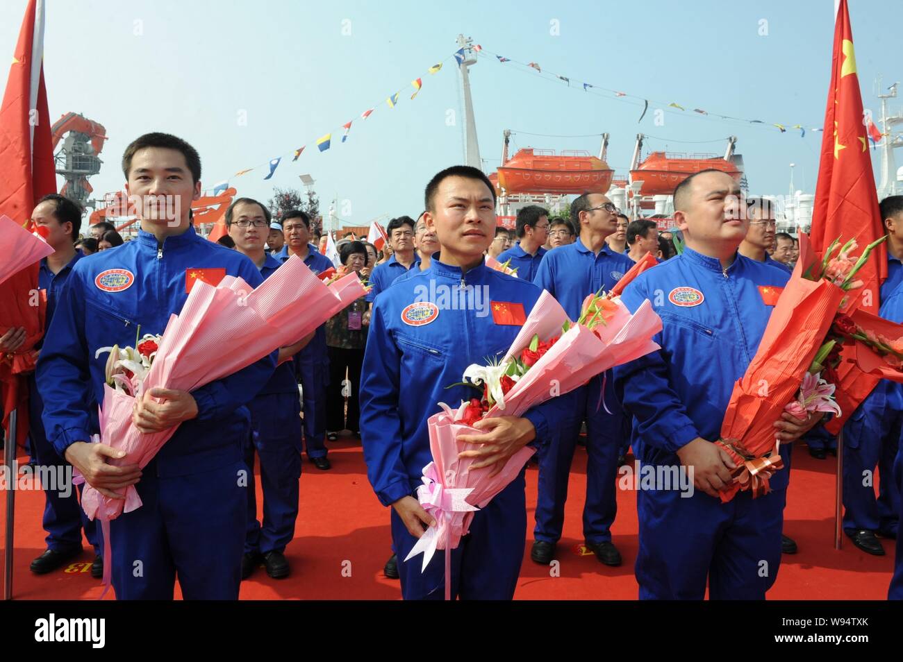 Cinese i membri del personale della nave oceanografica Xiangyanghong 09 portante Chinese manned deep-sea sommergibili, il Jiaolong, ricevere fiori a Qingda Foto Stock