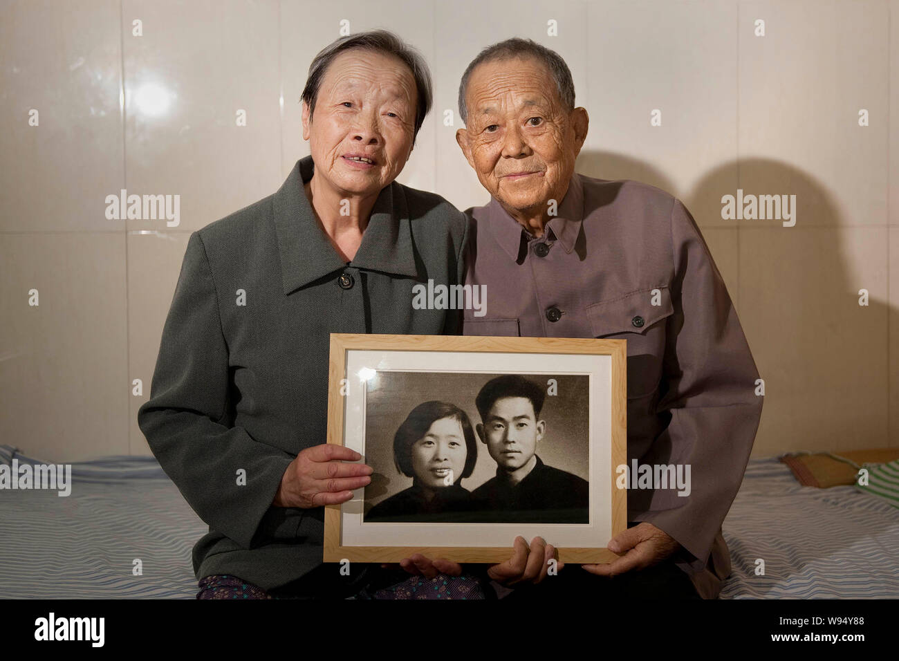73-year-old Jin Qianying, sinistro e il suo 80-anno-vecchio marito Wang Binglian chi soffre di uremia tenere il loro matrimonio foto preso 50 anni fa presso il reparto di un Foto Stock