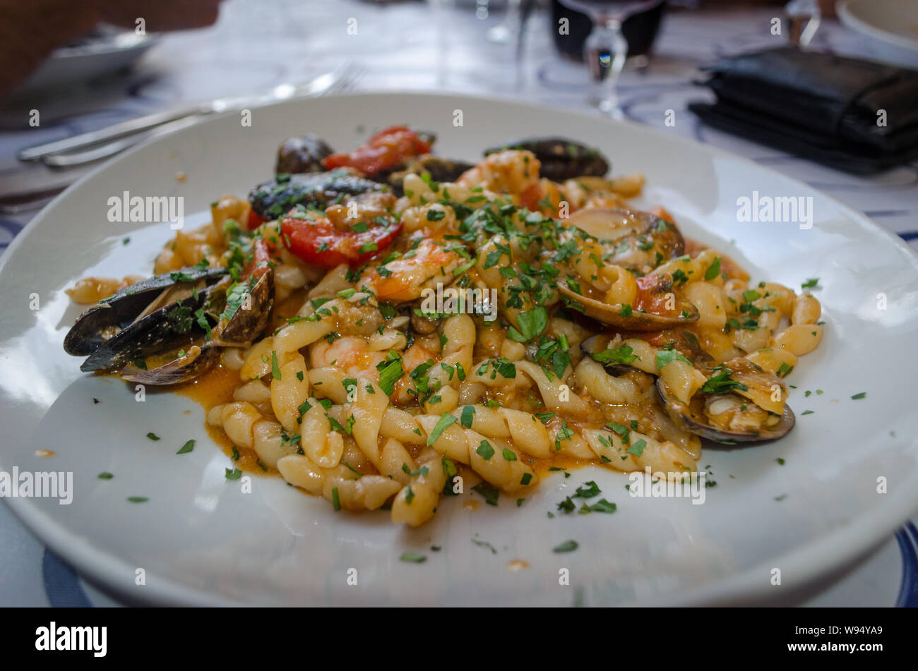 Cucina Italiana - Pasta con frutti di mare: i gamberetti, cozze, trancia di Pesce spada con verde di prezzemolo Foto Stock