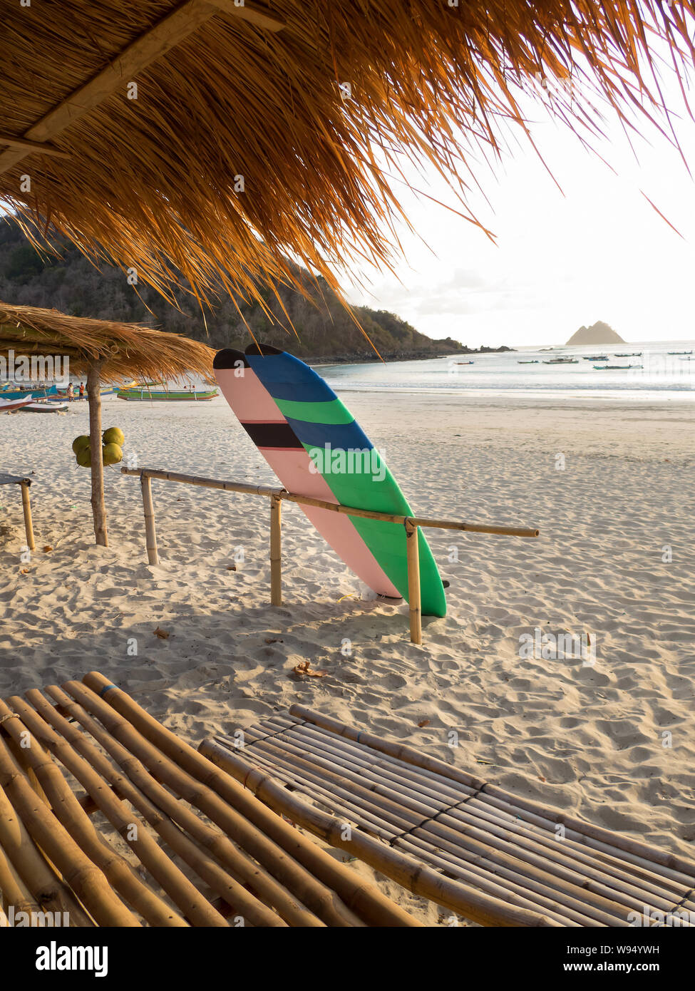 Colorate tavole da surf appoggiato su di un recinto di bambù sulla baia sabbiosa di Selong Belanak Beach in Lombok Foto Stock