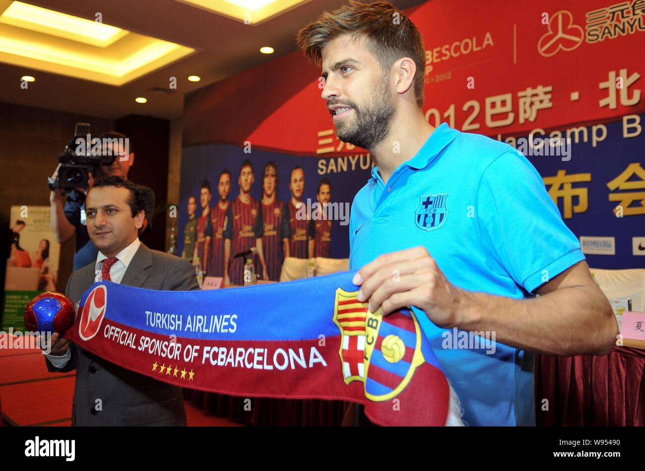 Lo spagnolo la star del calcio GERARD PIQUE (R) detiene una sciarpa durante una conferenza stampa per la creazione del FC Barcelona Youth Training Camp a Pechino, Chi Foto Stock