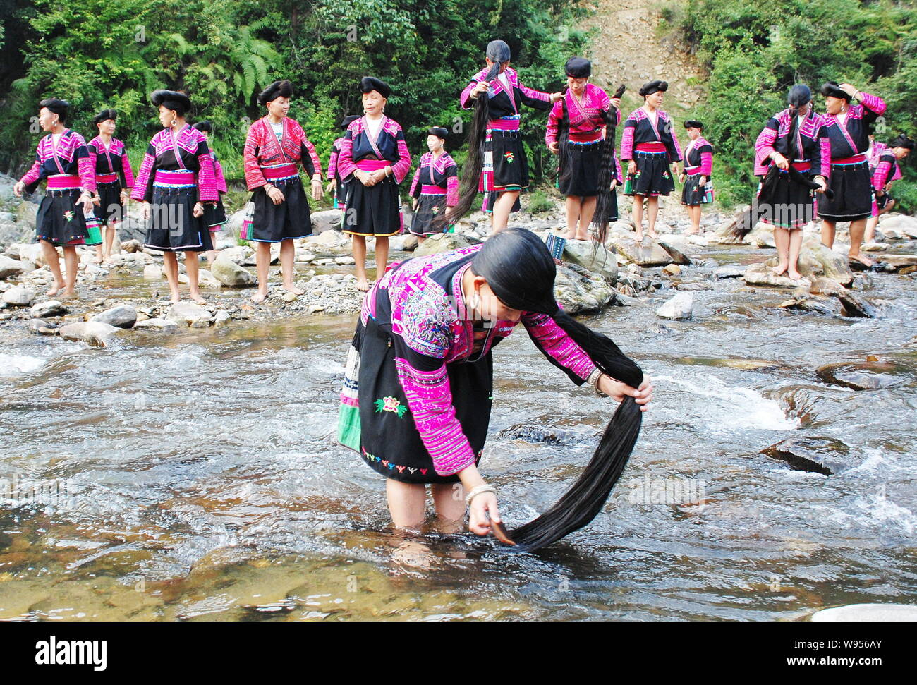 Le donne di Red Yao minoranza etnica gruppo lavarsi i capelli lunghi nel fiume in Huangluo Yao villaggio, Longsheng county, della città di Guilin, sud Chinas Guangxi Foto Stock