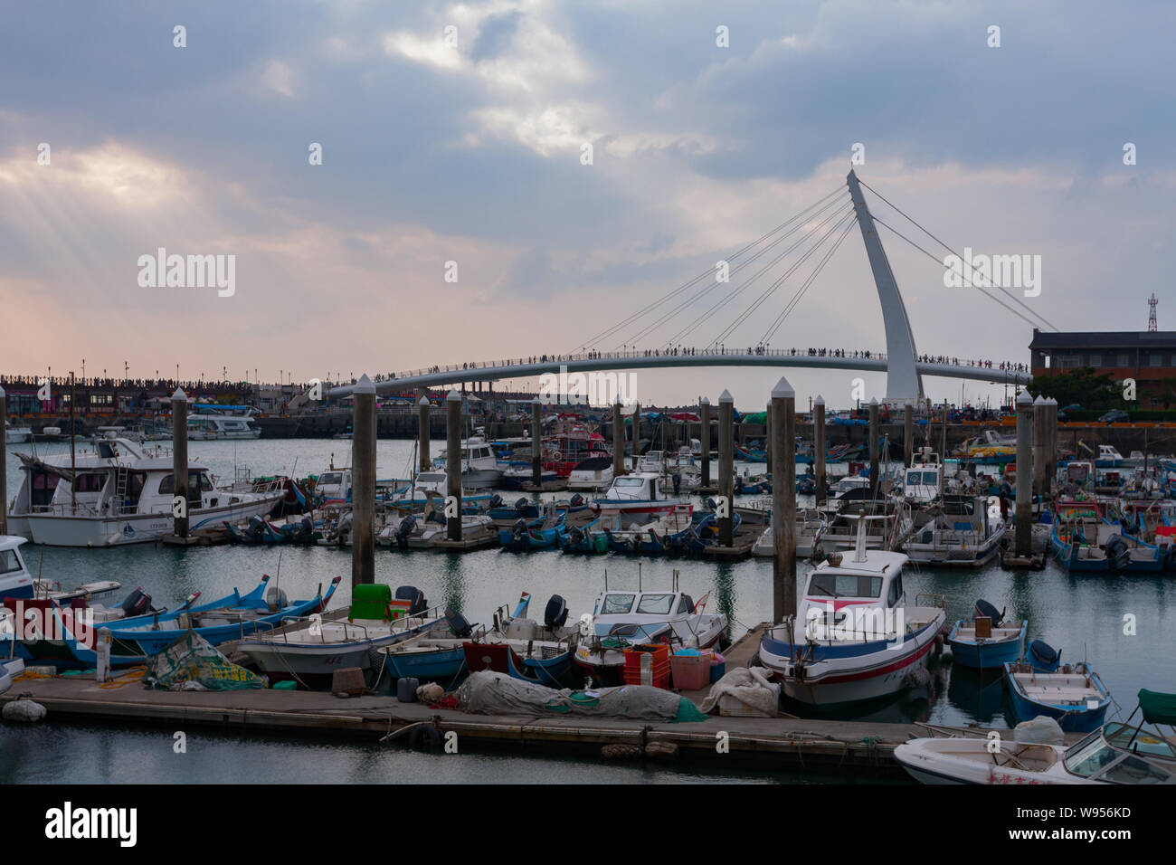 Raggi crepuscolari, flussi di luce del sole attraverso piccoli fori nelle nuvole, amante di ponte, le piccole imbarcazioni da pesca, Tamsui Fisherman Wharf, Taipei, Taiwan Foto Stock