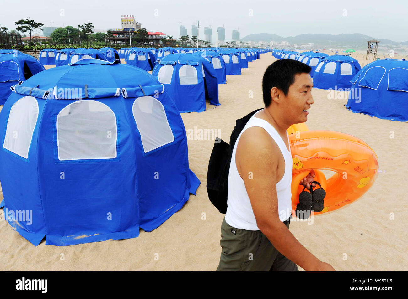 Una passeggiate turistiche passato tende da campeggio sulla spiaggia di sabbia dorata a Qingdao City East Chinas provincia di Shandong, 26 luglio 2012. Un totale di 1.000 tende wil Foto Stock