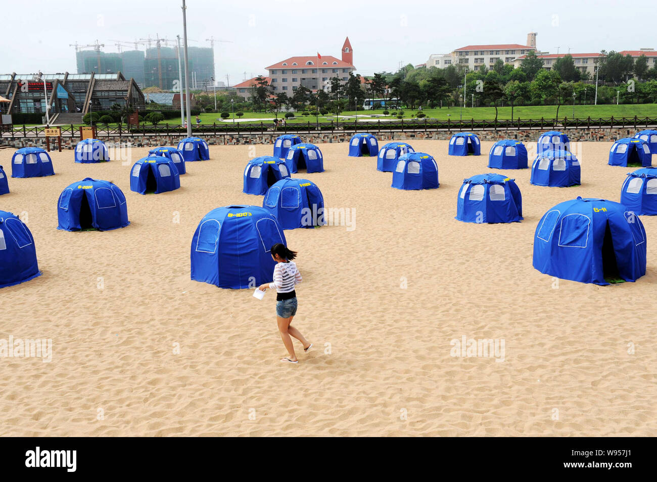 Una passeggiate turistiche passato tende da campeggio sulla spiaggia di sabbia dorata a Qingdao City East Chinas provincia di Shandong, 26 luglio 2012. Un totale di 1.000 tende wil Foto Stock