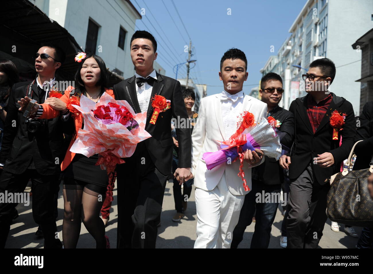 Il cinese coppia gay Lu Zhong, la terza a destra e Liu Wanqiang, la terza a sinistra, camminare sulla strada durante la loro cerimonia di nozze nella contea Zherong, Ningde cit Foto Stock