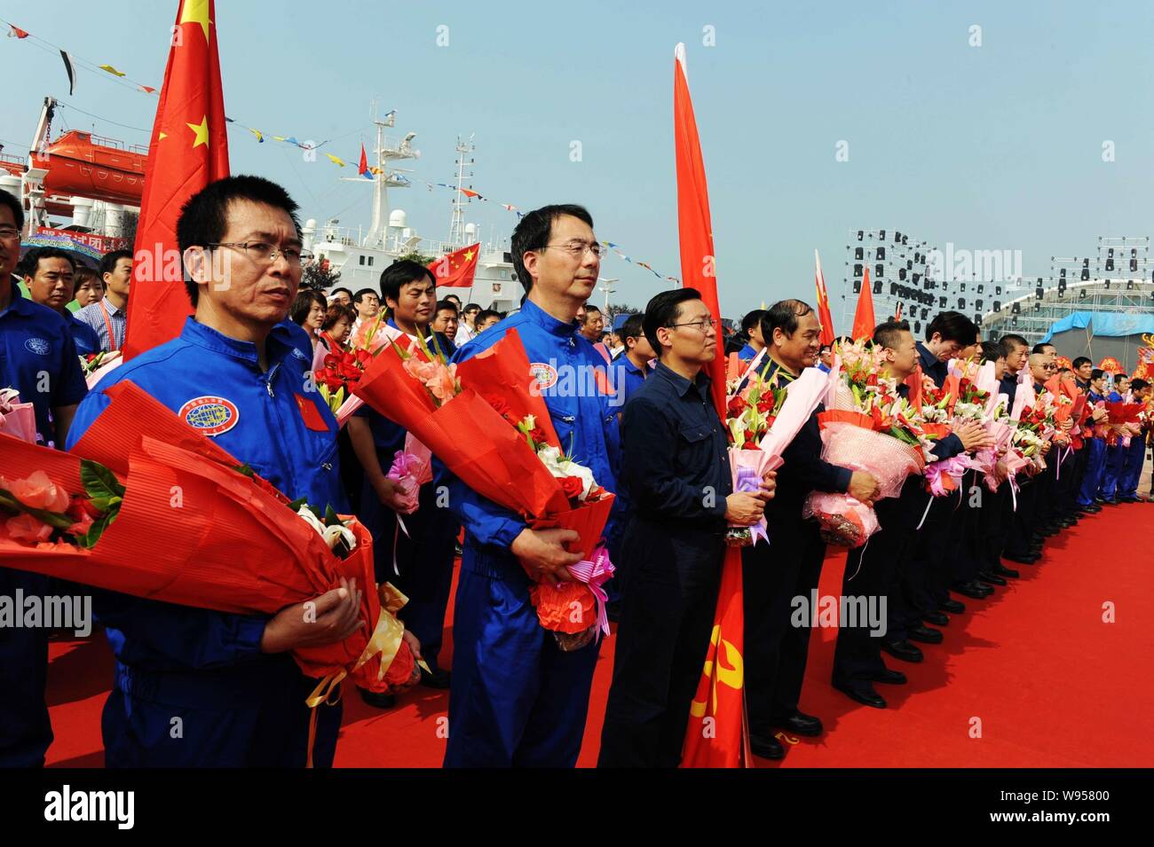 Cinese i membri del personale della nave oceanografica Xiangyanghong 09 portante Chinese manned deep-sea sommergibili, il Jiaolong, ricevere fiori a Qingda Foto Stock