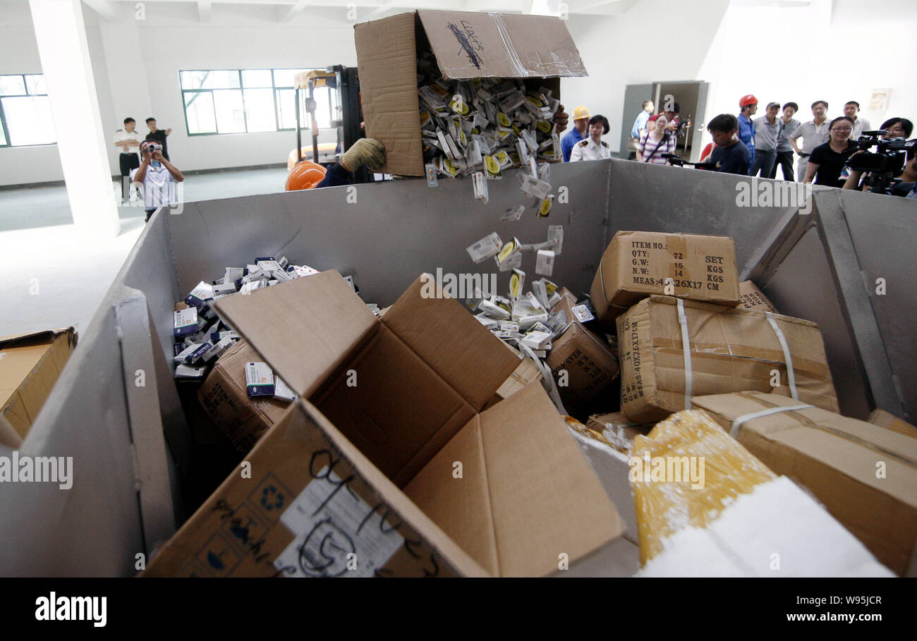 Lavoratori cinesi pour fake pillole di Viagra e altre merci contraffatte per essere distrutti in un contenitore in un impianto a Shanghai in Cina, 24 luglio 2012. Sha Foto Stock
