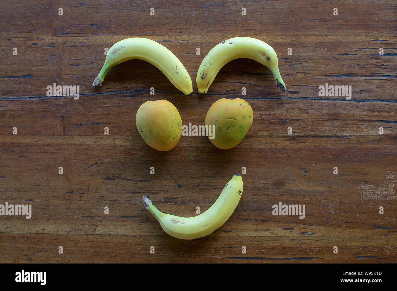 Un volto sorridente realizzata in diversi tipi di frutta su un tavolo di legno Foto Stock