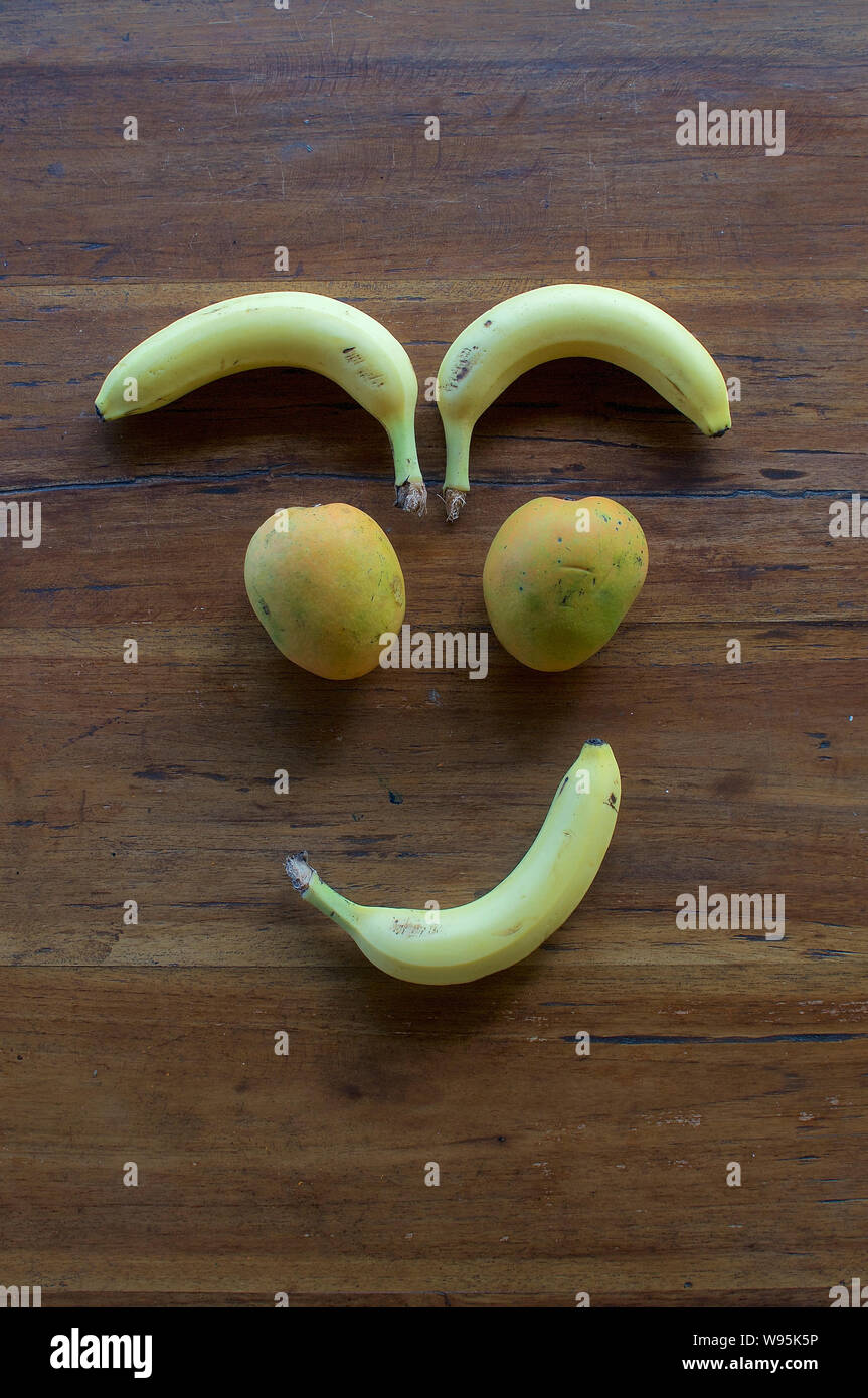 Un volto sorridente realizzata in diversi tipi di frutta su un tavolo di legno Foto Stock