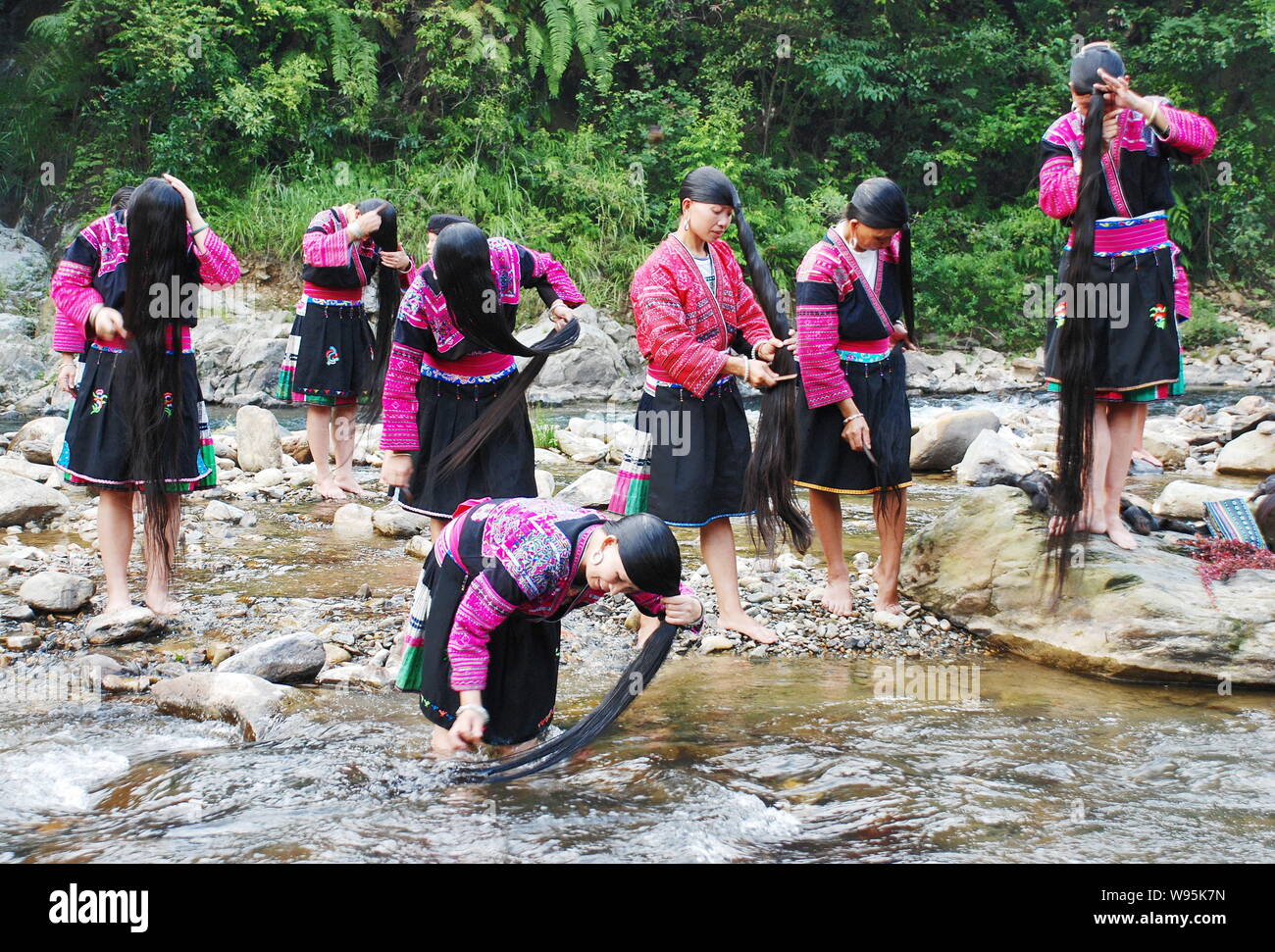 Le donne di Red Yao minoranza etnica gruppo lavarsi i capelli lunghi nel fiume in Huangluo Yao villaggio, Longsheng county, della città di Guilin, sud Chinas Guangxi Foto Stock