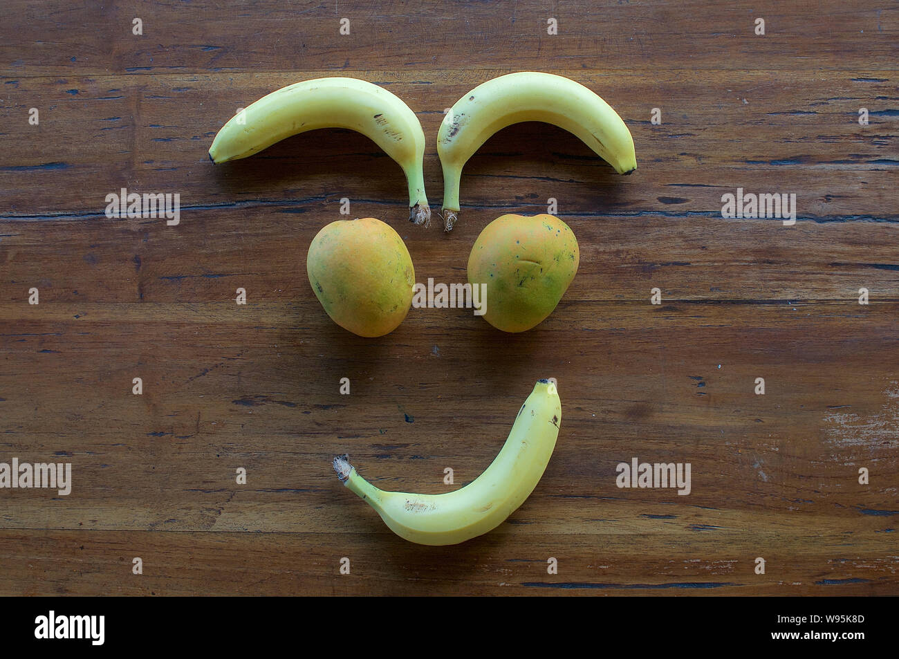 Un volto sorridente realizzata in diversi tipi di frutta su un tavolo di legno Foto Stock