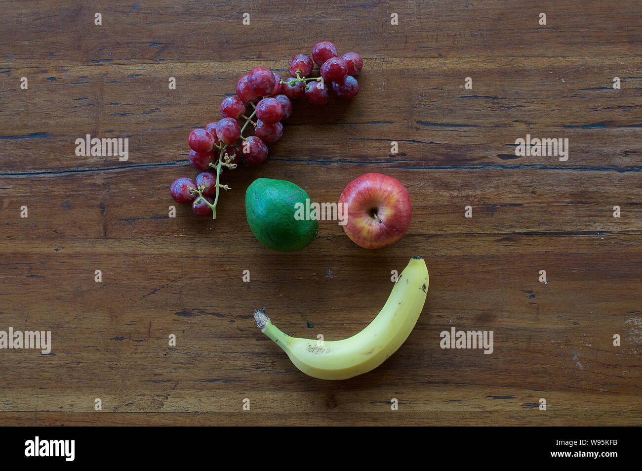 Un volto sorridente realizzata in diversi tipi di frutta su un tavolo di legno Foto Stock