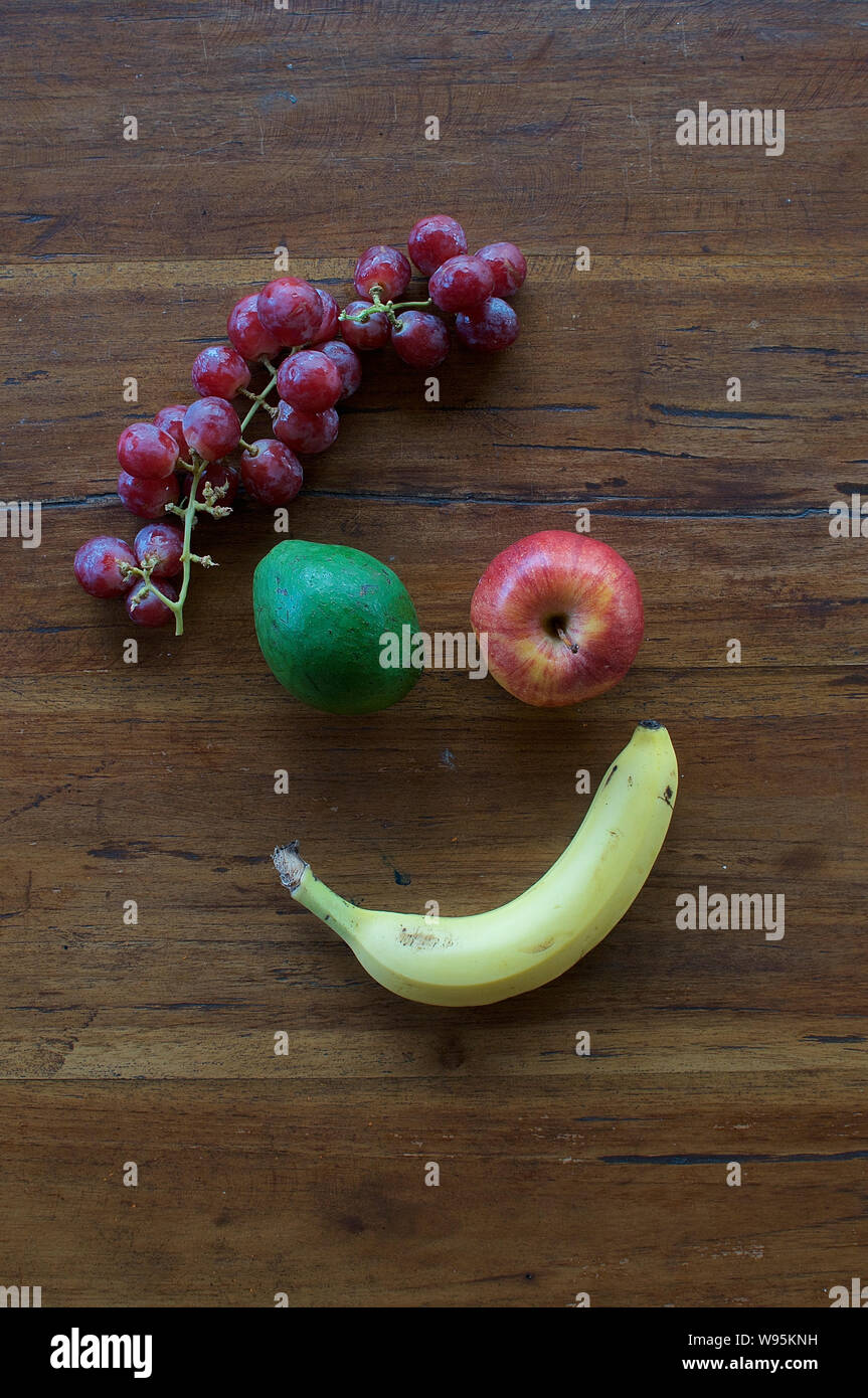 Un volto sorridente realizzata in diversi tipi di frutta su un tavolo di legno Foto Stock