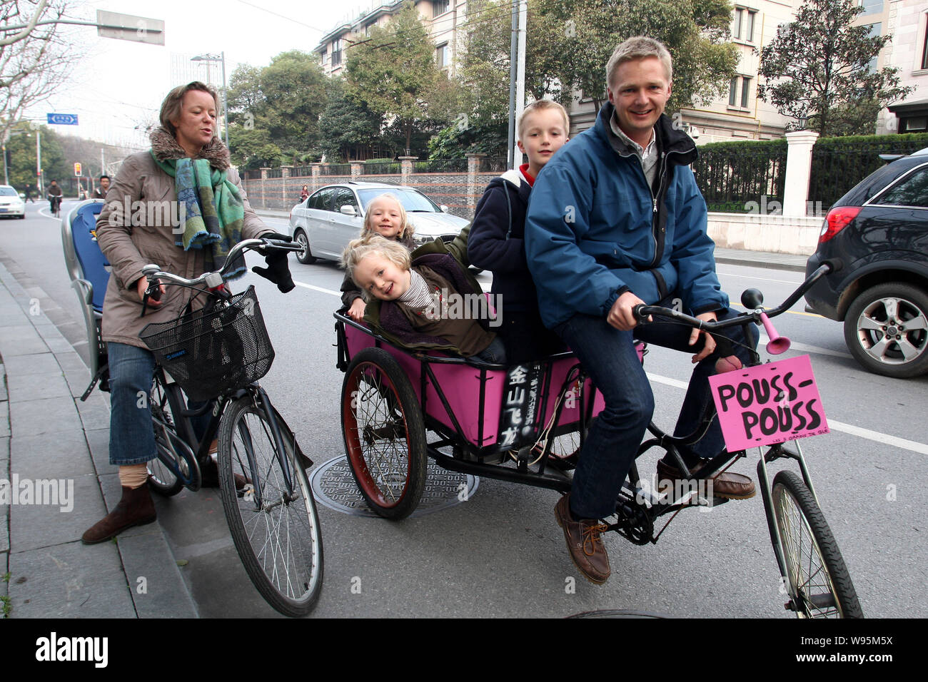 Il francese Loic Delcroix, a destra di un responsabile finanziario di Dongfeng Citroen, e la sua famiglia amano le loro escursioni in bicicletta su un triciclo e una bici in strada Foto Stock