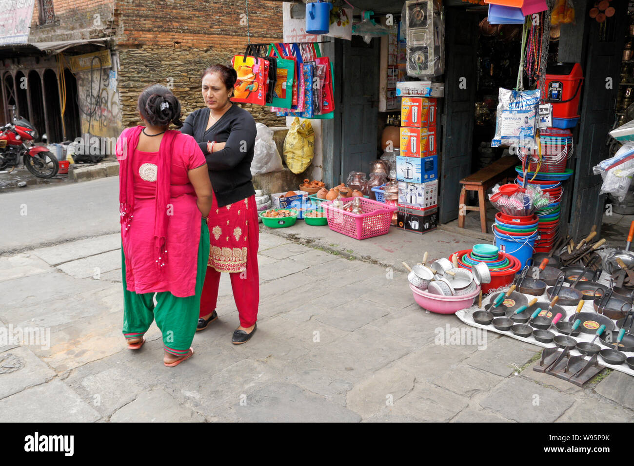 Le donne in abito tradizionale in piedi al di fuori di un negozio nel Vecchio Bazar area di Pokhara, Nepal Foto Stock