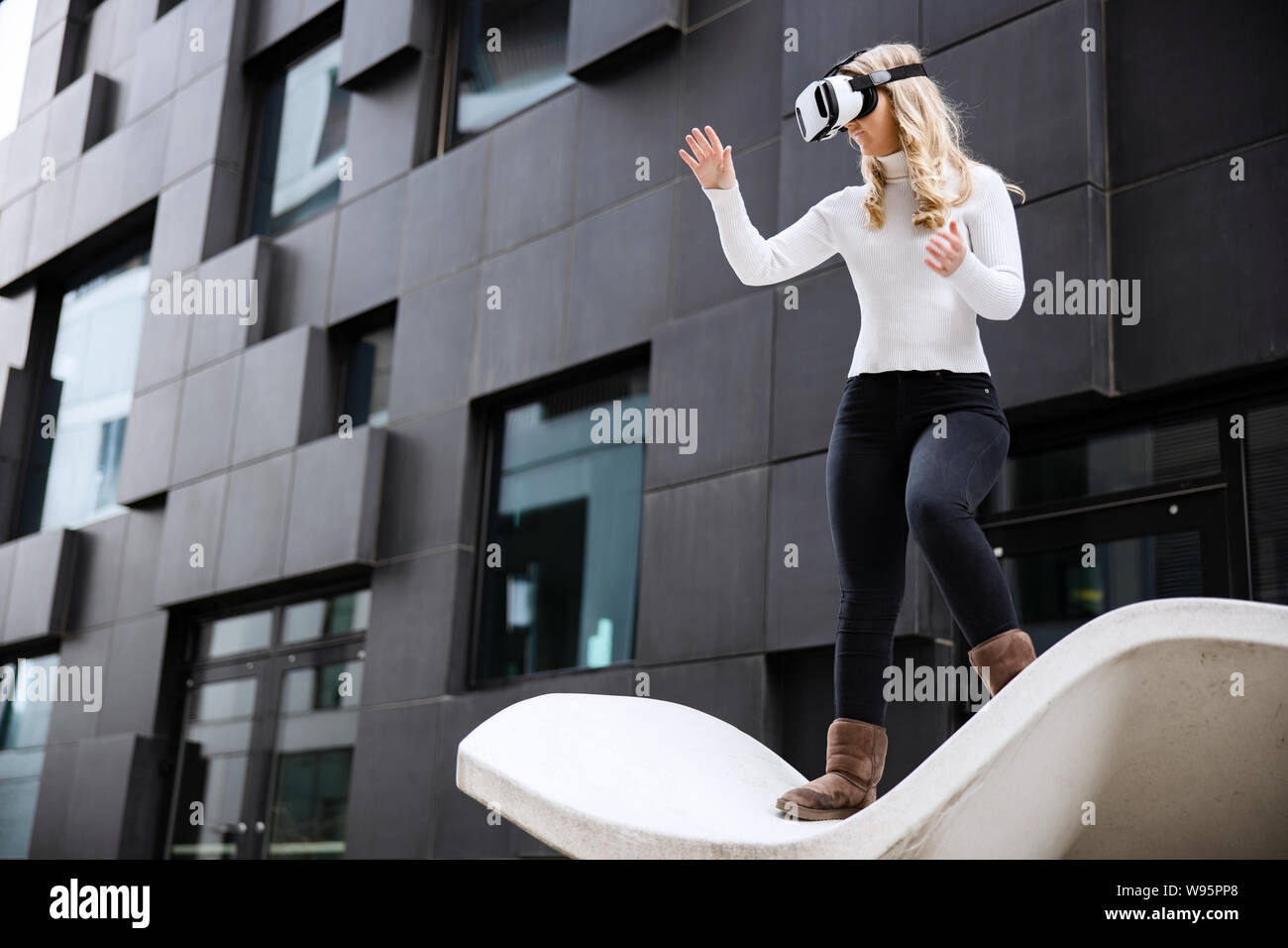 Donna che utilizza occhiali per realtà virtuale tecnologia contro edificio futuristico Foto Stock