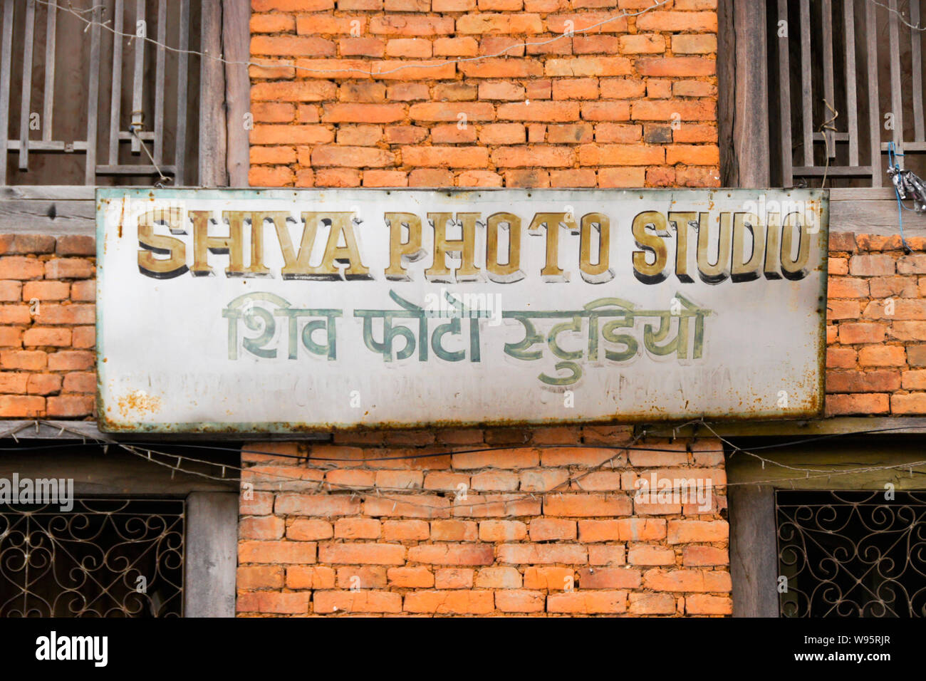 Cartello bilingue (inglese e nepalese) su un vecchio edificio in mattoni nel Vecchio Bazar area di Pokhara, Nepal Foto Stock