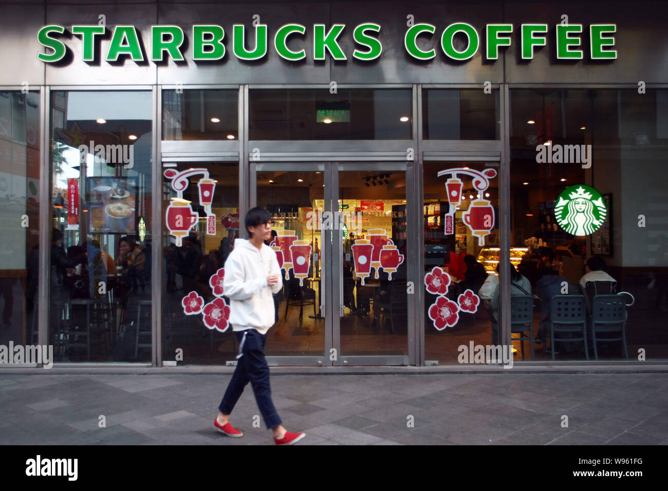 --File--un uomo cammina passato presso un caffè Starbucks Cafe in Cina a Shanghai, 31 gennaio 2012. Starbucks Corp. è la pianificazione di una maggiore spinta in piccole citi Foto Stock