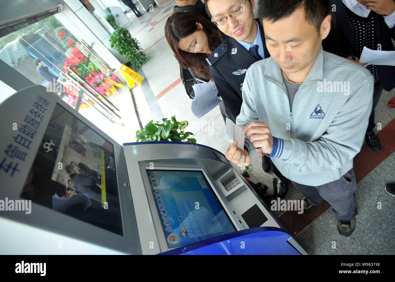 Un uomo tenta di eseguire un terminale self service per rinnovare la patente di guida a Chongqing Cina, 20 novembre 2011. Foto Stock