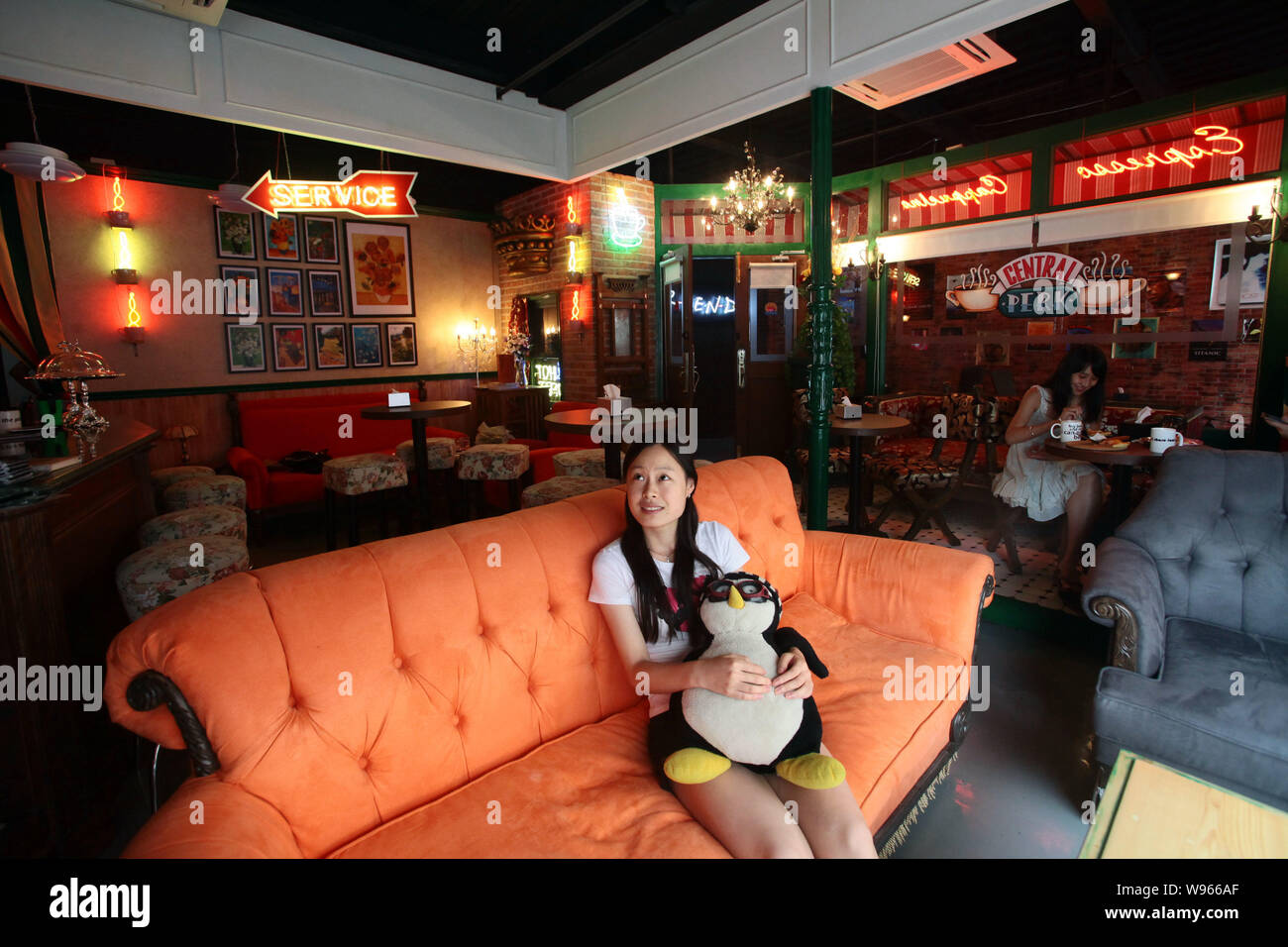 Una giovane donna seduta nel lettino arancione orologi DVD della serie TV con gli amici in un Central Perk cafe a Shanghai in Cina, 3 settembre 2012. Central Foto Stock