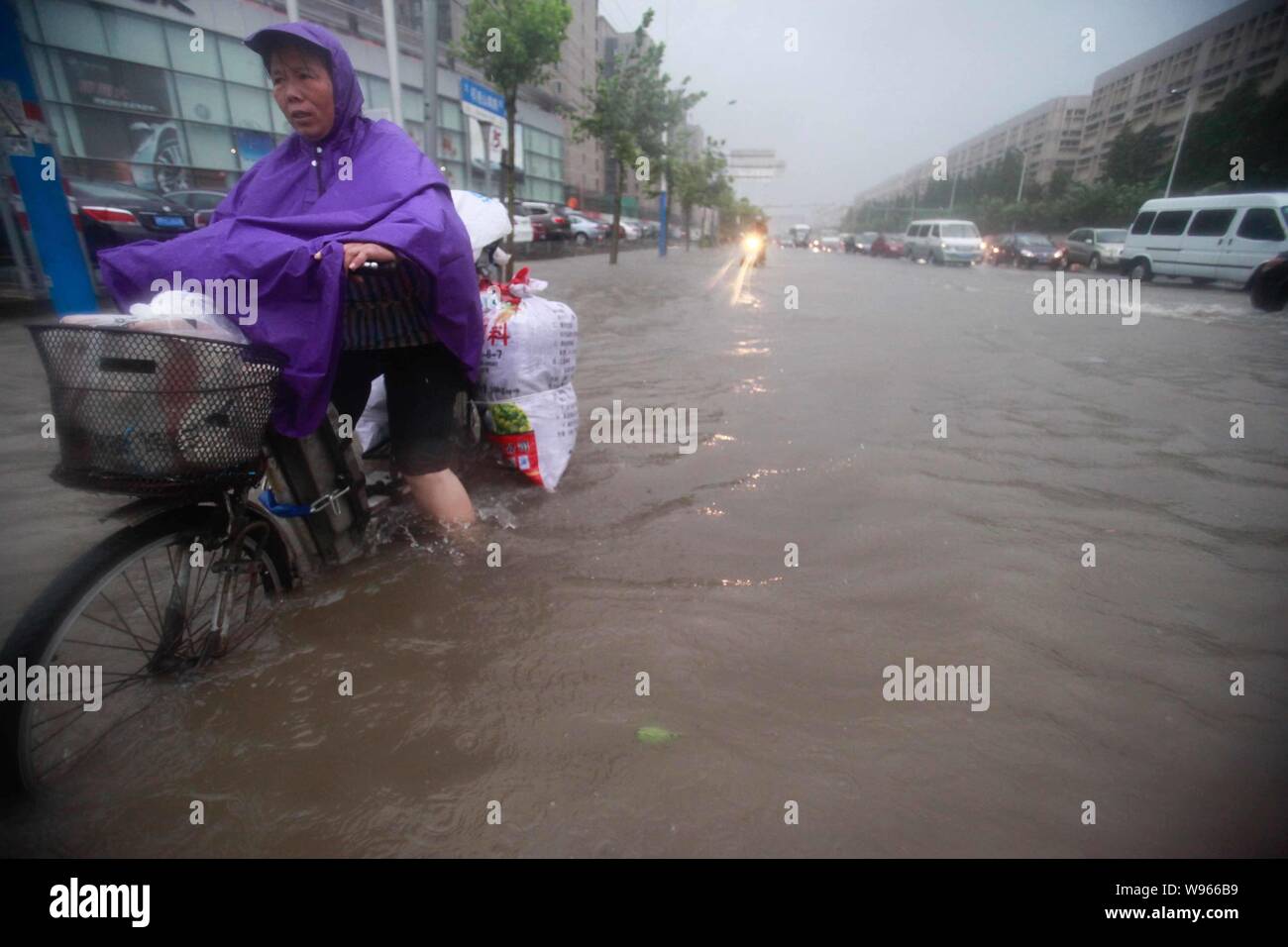 I ciclisti e i veicoli brave inondazioni su una strada in forte pioggia causata dal tifone Haikui in Cina a Shanghai, 8 agosto 2012. Il terzo ciclone tropicale in Foto Stock
