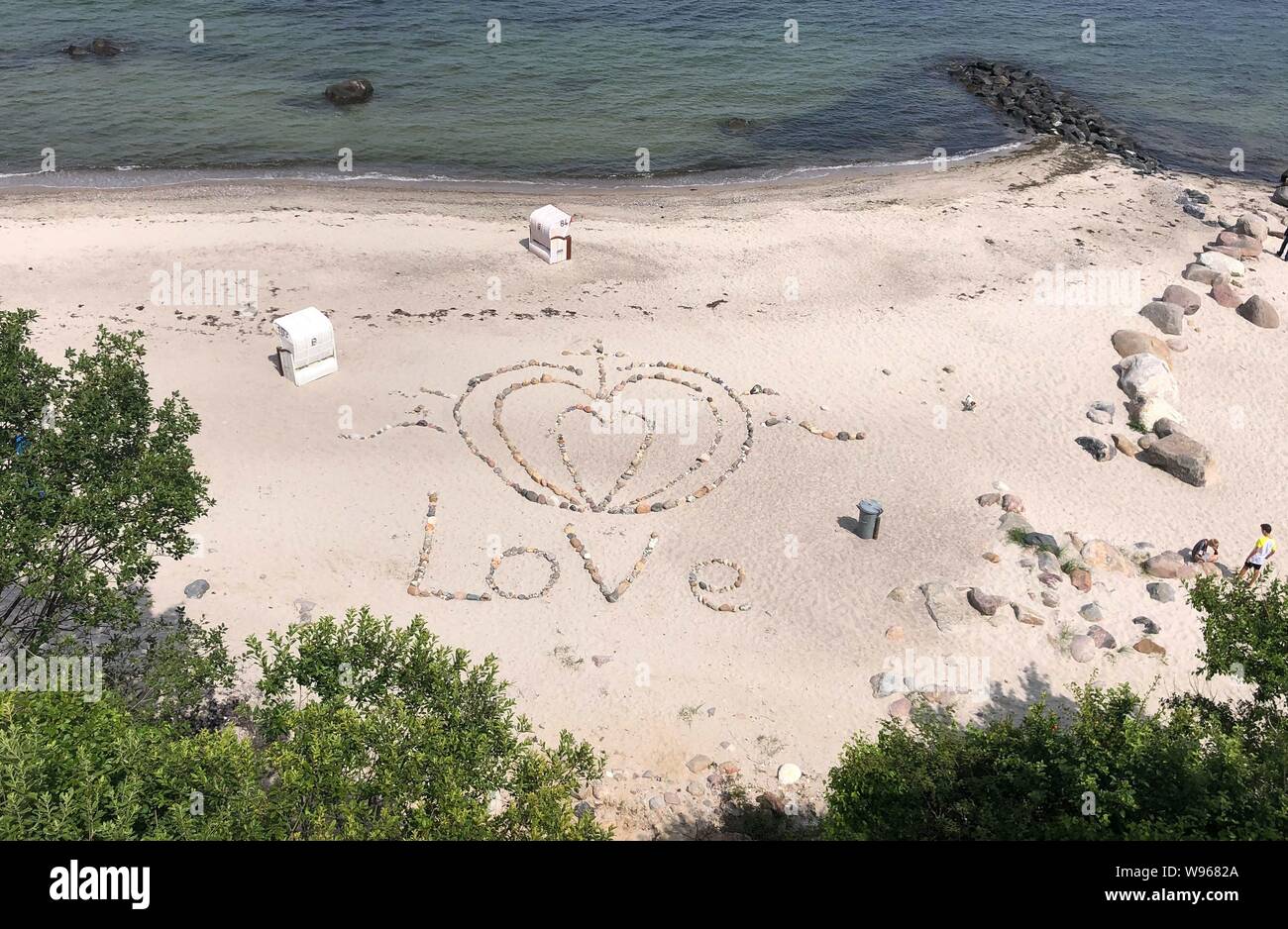 Hohwacht, Deutschland. 17 Luglio, 2019. firo: 16.07.2019 Turismo Terra e la gente, paesaggio, Mar Baltico, vacanze, Schleswig-Holstein, Hohwachter Bucht Wetterbild, HOLSTEINISCHE SVIZZERA, sabbia, spiaggia, mare, amore segno di Pietre e conchiglie sulla spiaggia di HOHWACHT. | Utilizzo di credito in tutto il mondo: dpa/Alamy Live News Foto Stock