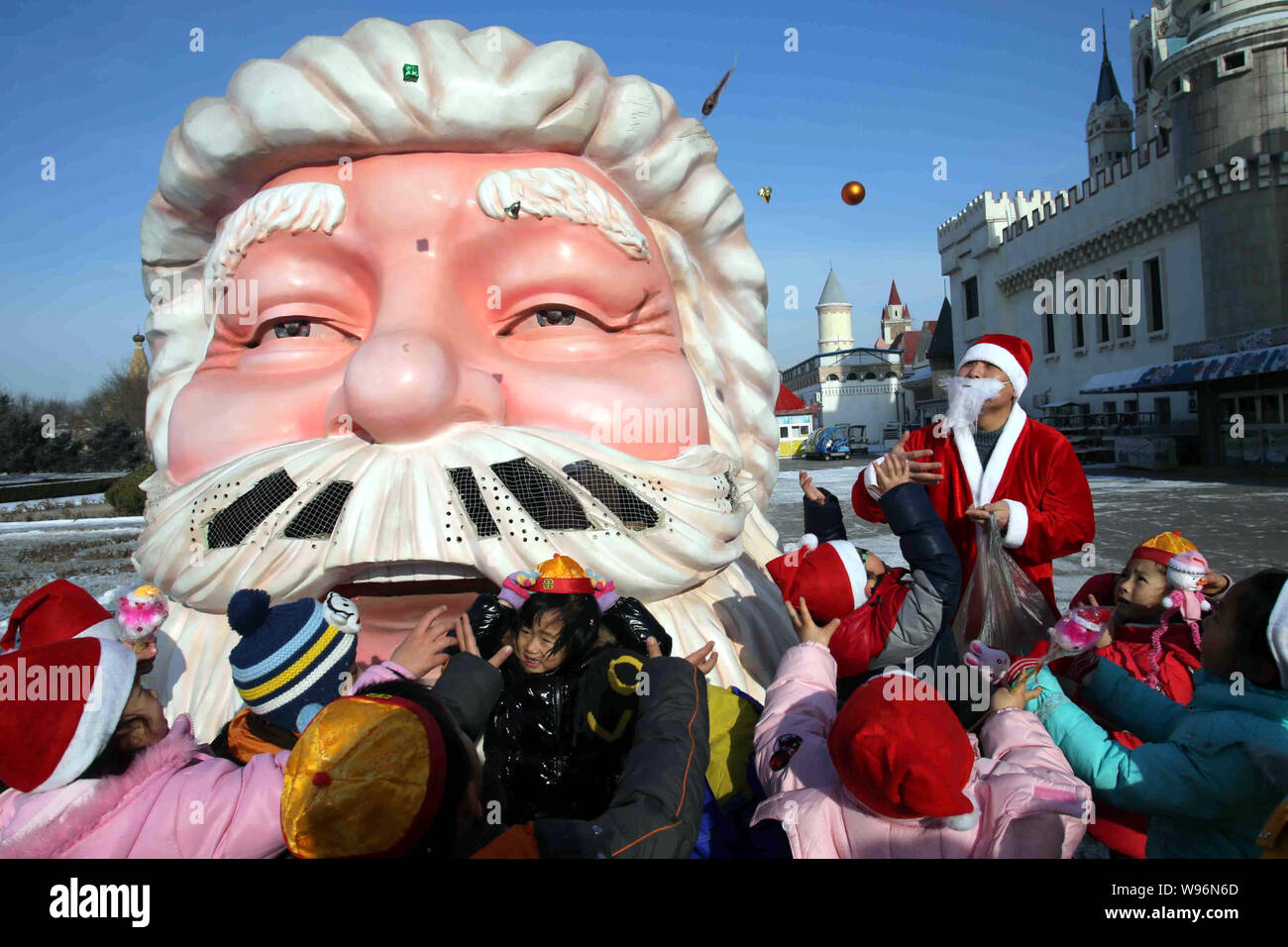 Un giovane uomo cinese vestito di una Santa Claus costume distribuisce doni ai bambini per festeggiare il Natale presso il Beijing World Park a Pechino, Cina Foto Stock