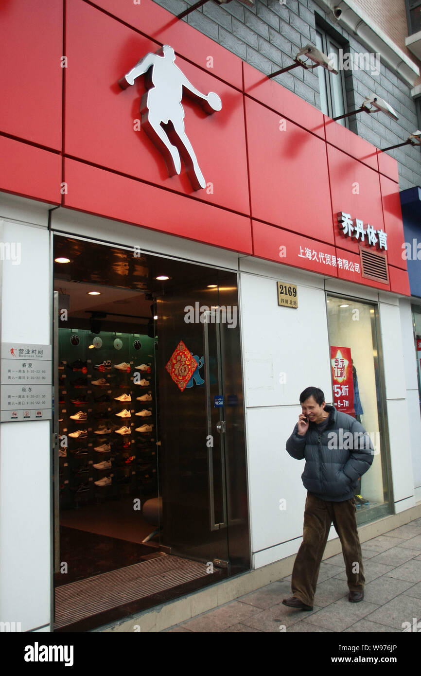 Un pedone cammina davanti a un negozio di abbigliamento sportivo di  Qiaodan, la traduzione cinese di Giordania, in Cina a Shanghai, 23 febbraio  2012. Michael Jordan, h Foto stock - Alamy