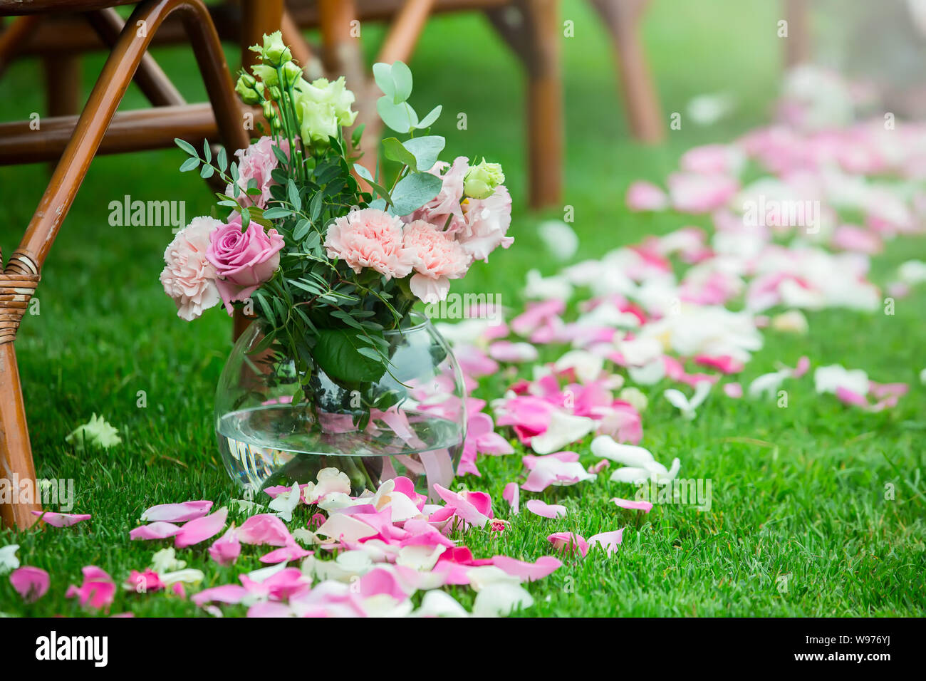 Outdoor cerimonia nuziale decorazione setup. Percorso con petali, sedie decorate con nastri colorati Foto Stock