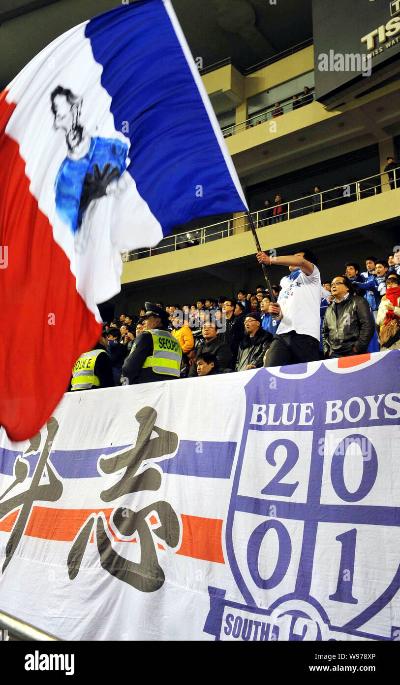 Un ventilatore cinese di Shanghai Shenhua onde francese la bandiera  nazionale con un cartone animato immagine dell'attaccante francese Nicolas  Anelka nel match tra Shanghai S Foto stock - Alamy