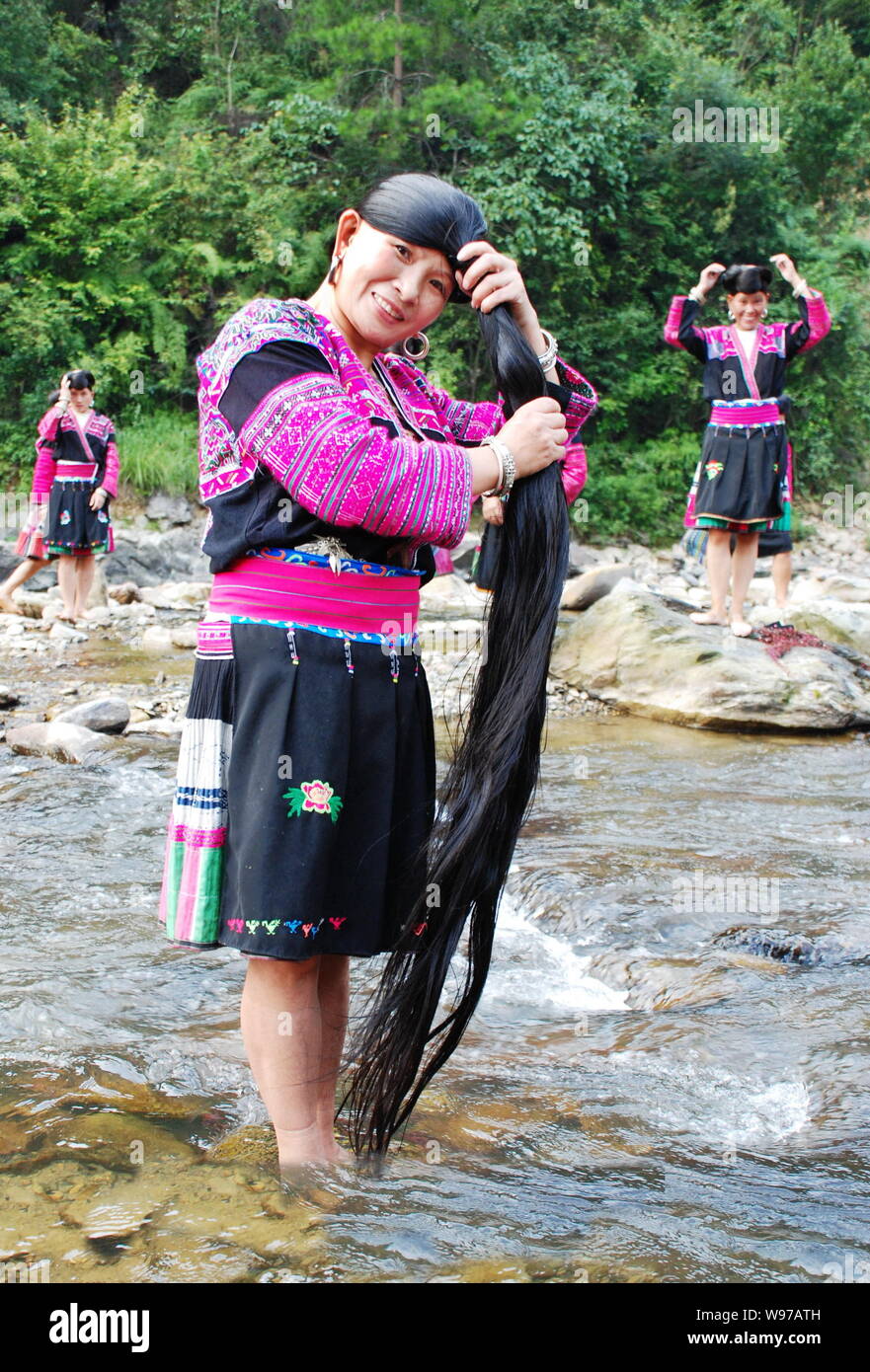 Le donne di Red Yao minoranza etnica gruppo lavarsi i capelli lunghi nel fiume in Huangluo Yao villaggio, Longsheng county, della città di Guilin, sud Chinas Guangxi Foto Stock