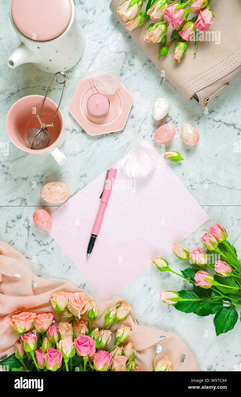 Accogliendo la molla come tema Laico piana tea break con le rose rosa e accessori femminili sul pavimento di marmo bianco dello sfondo. Foto Stock
