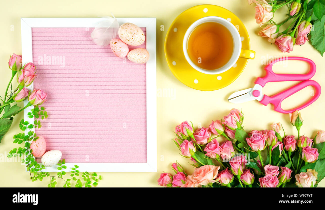 Accogliente primavera rosa e giallo tema Laico piana tea break con rose e accessori per il giardinaggio. Foto Stock