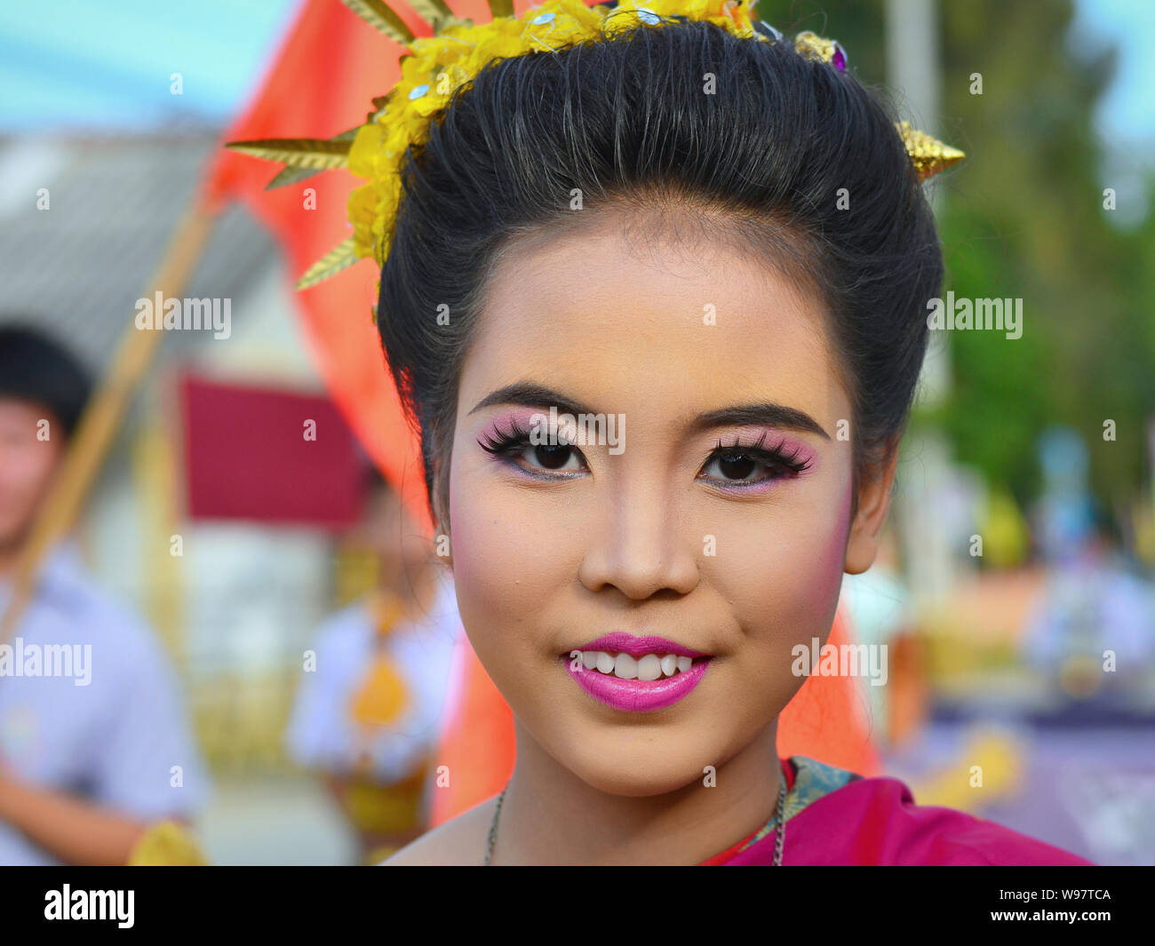 Vestite tailandese graziosa ragazza con i fiori nei capelli prende parte del villaggio Lanna storico street parade e sorrisi per la fotocamera. Foto Stock